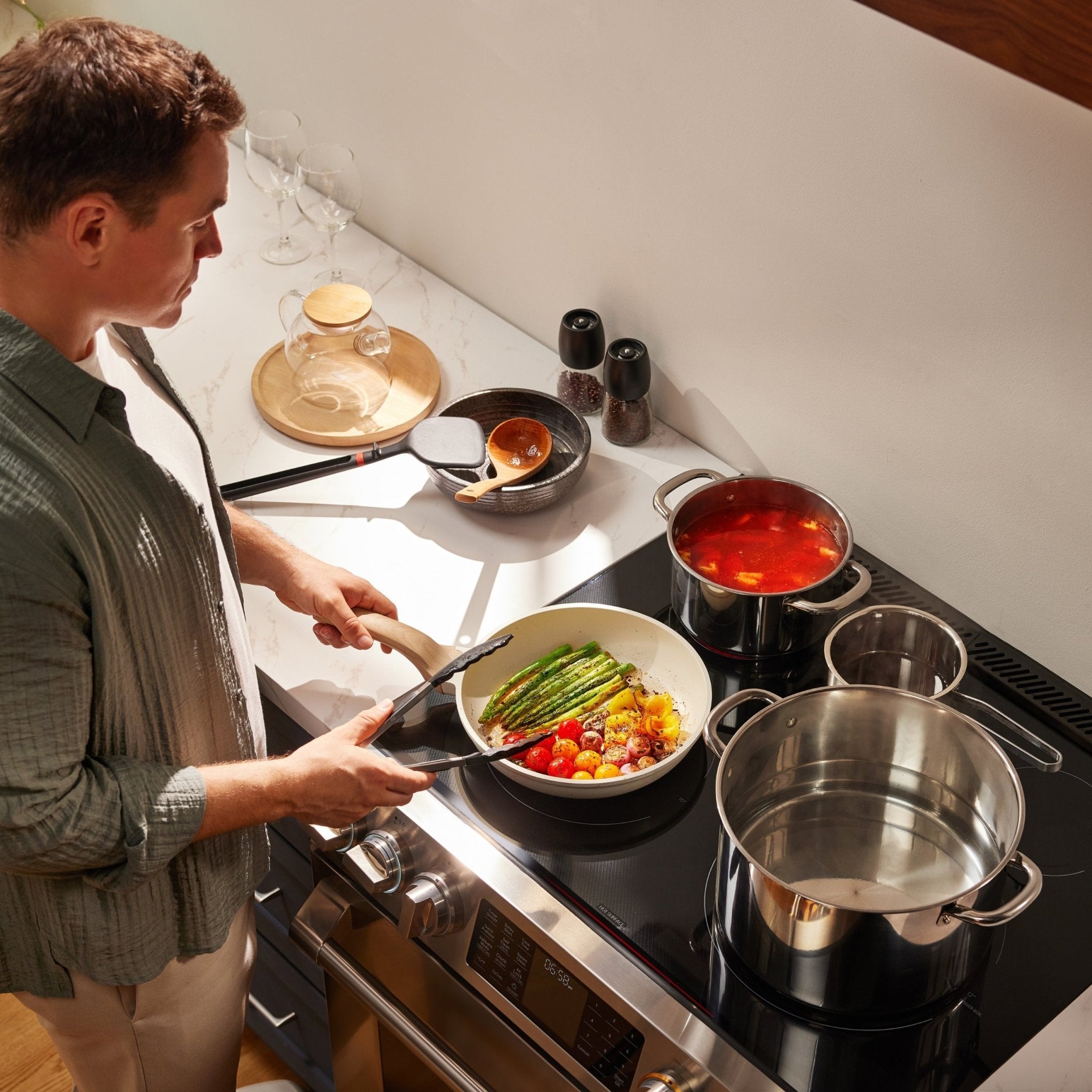 Stainless slide-in electric range with cookware on the cooktop during cooking