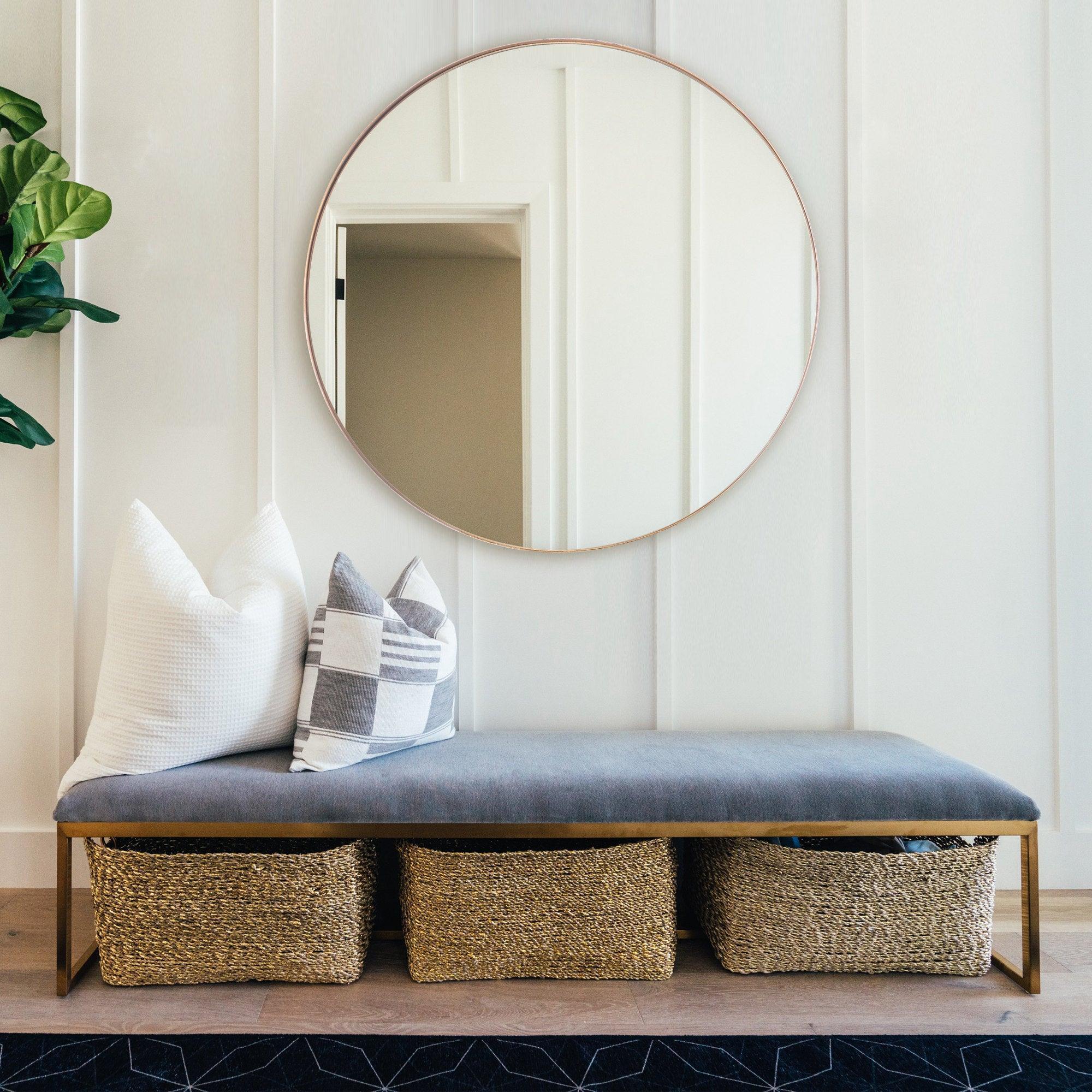 Round wall mirror with thin golden frame and reflective glass center.
