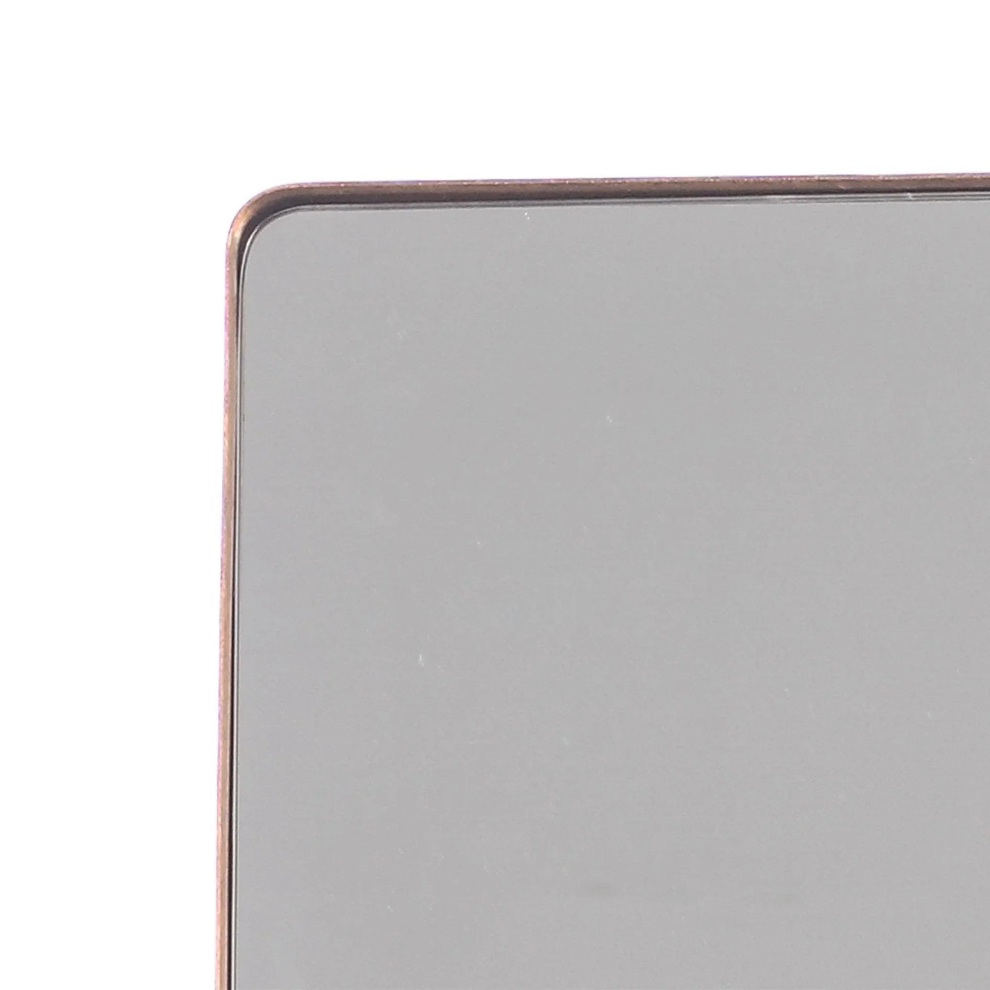 Close-up of gold-toned metal frame corner with rounded edge on square mirror