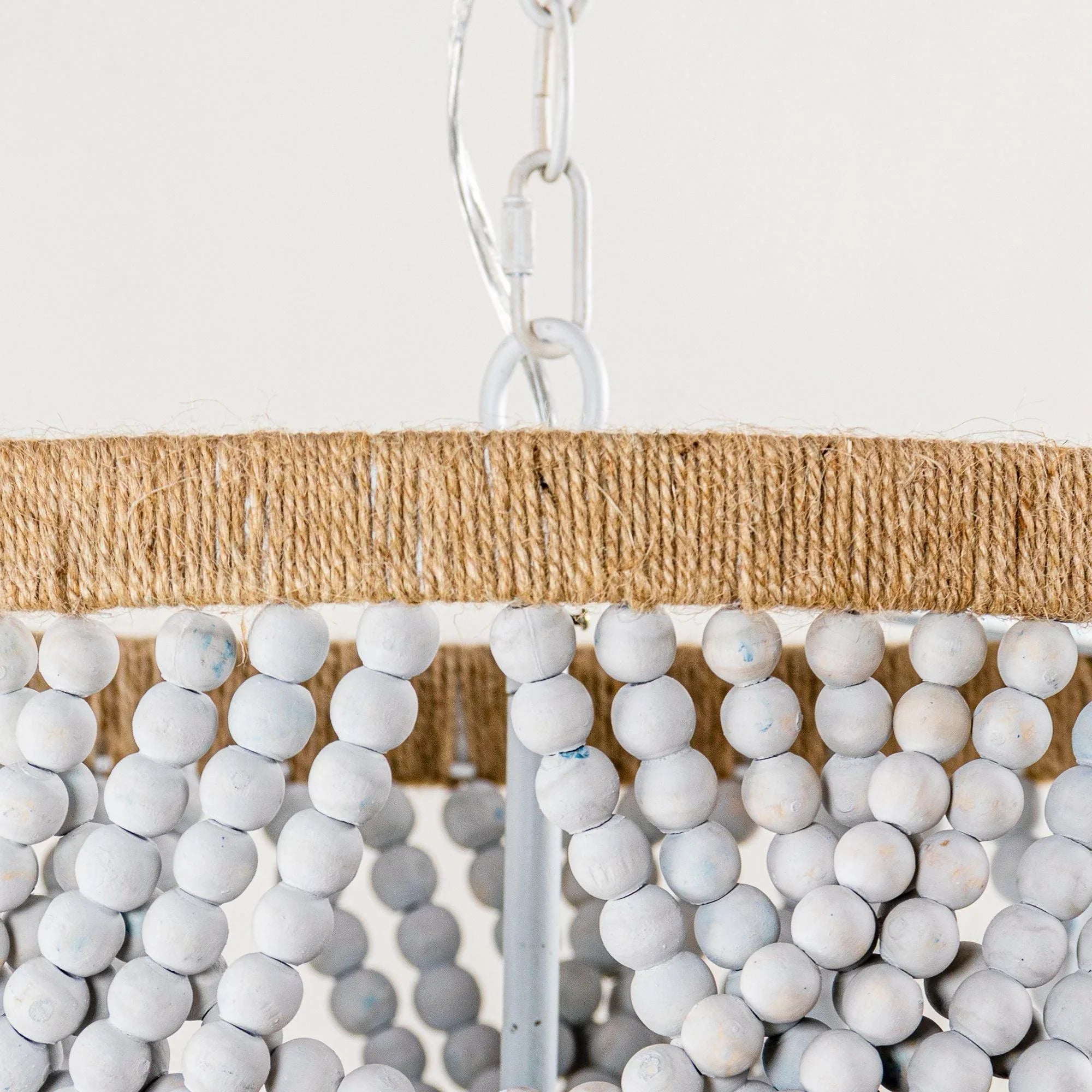 Top rim of beaded chandelier with beige fabric border and white bead strands