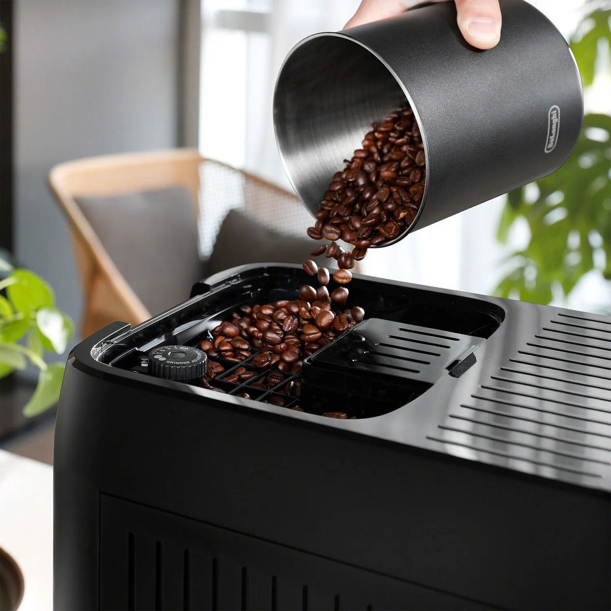 Coffee bean hopper pouring roasted beans into espresso machine grinder chute