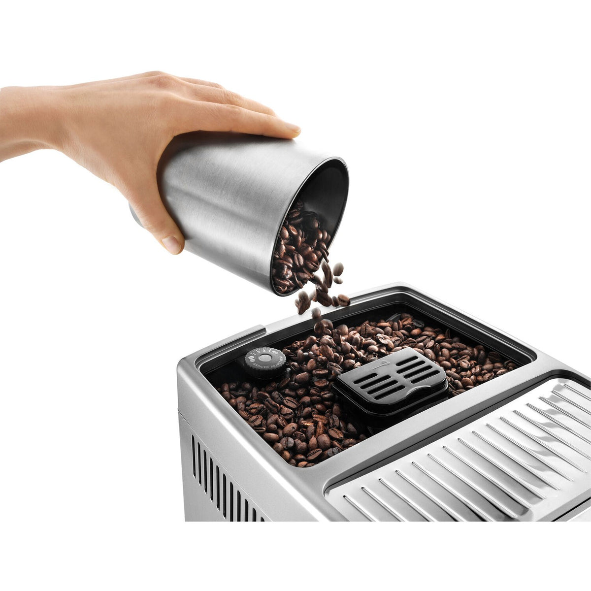Silver bean hopper being filled with dark coffee beans by a hand