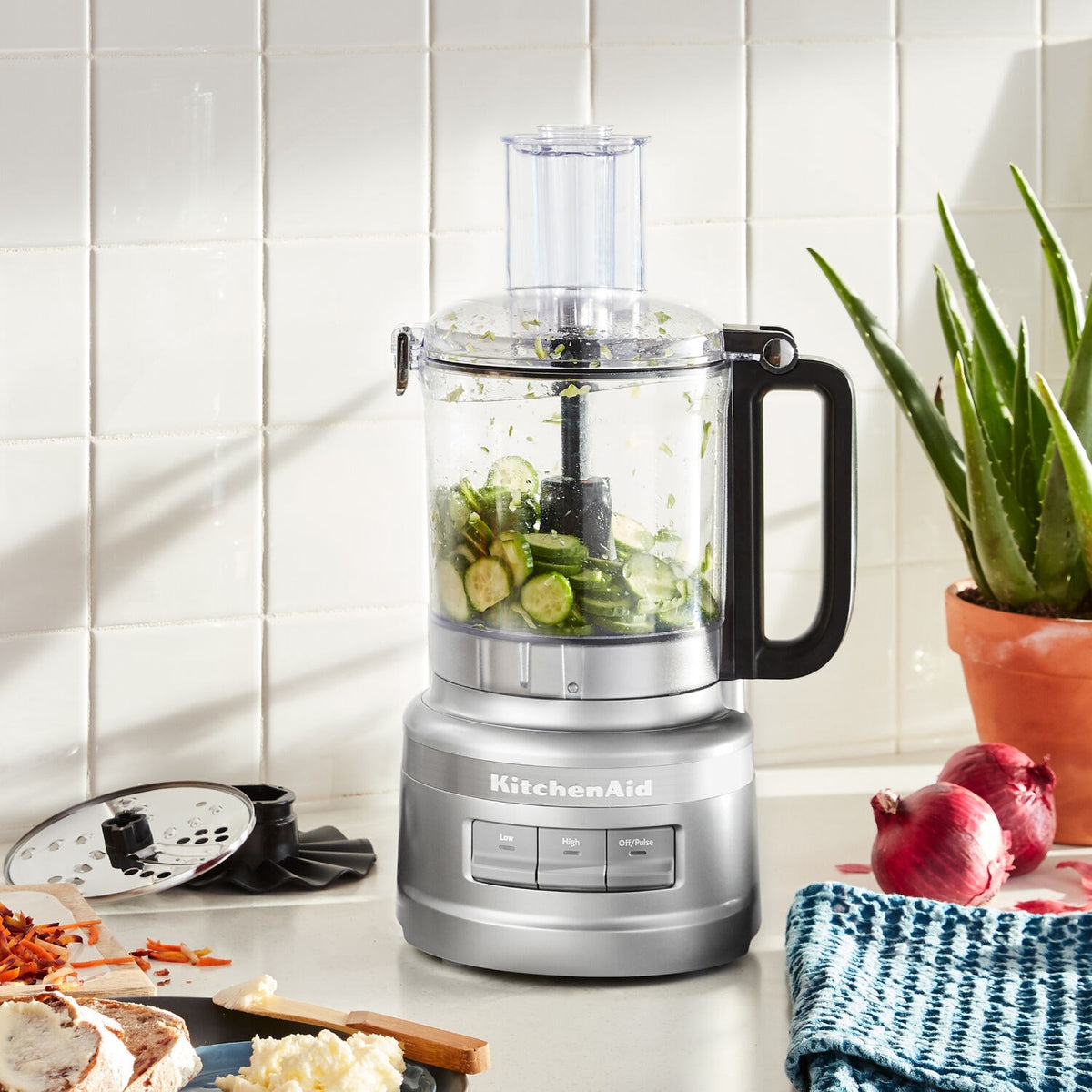 KitchenAid food processor with clear bowl and silver base on countertop