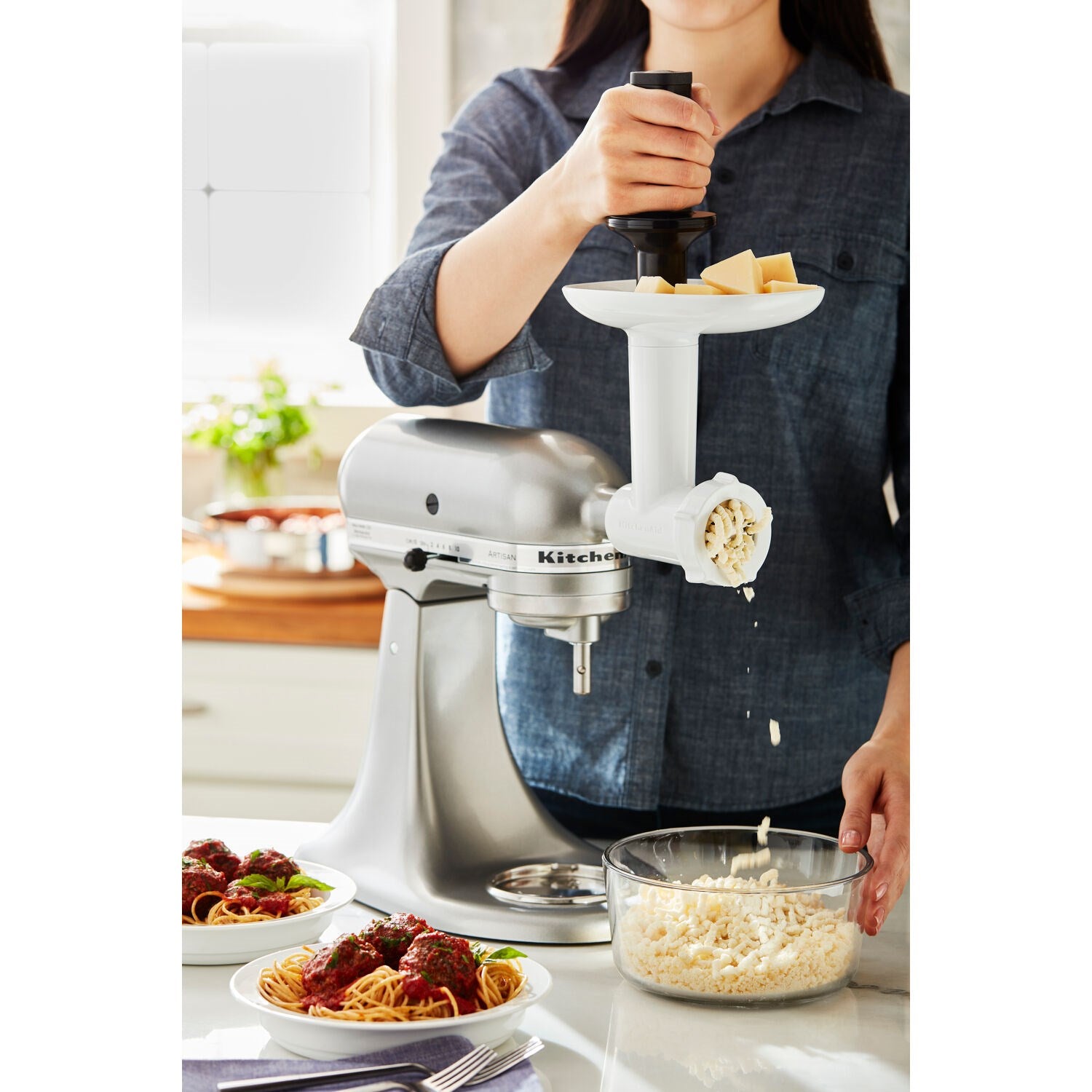 Food grinder attachment feeding ingredients into stand mixer bowl, with pusher