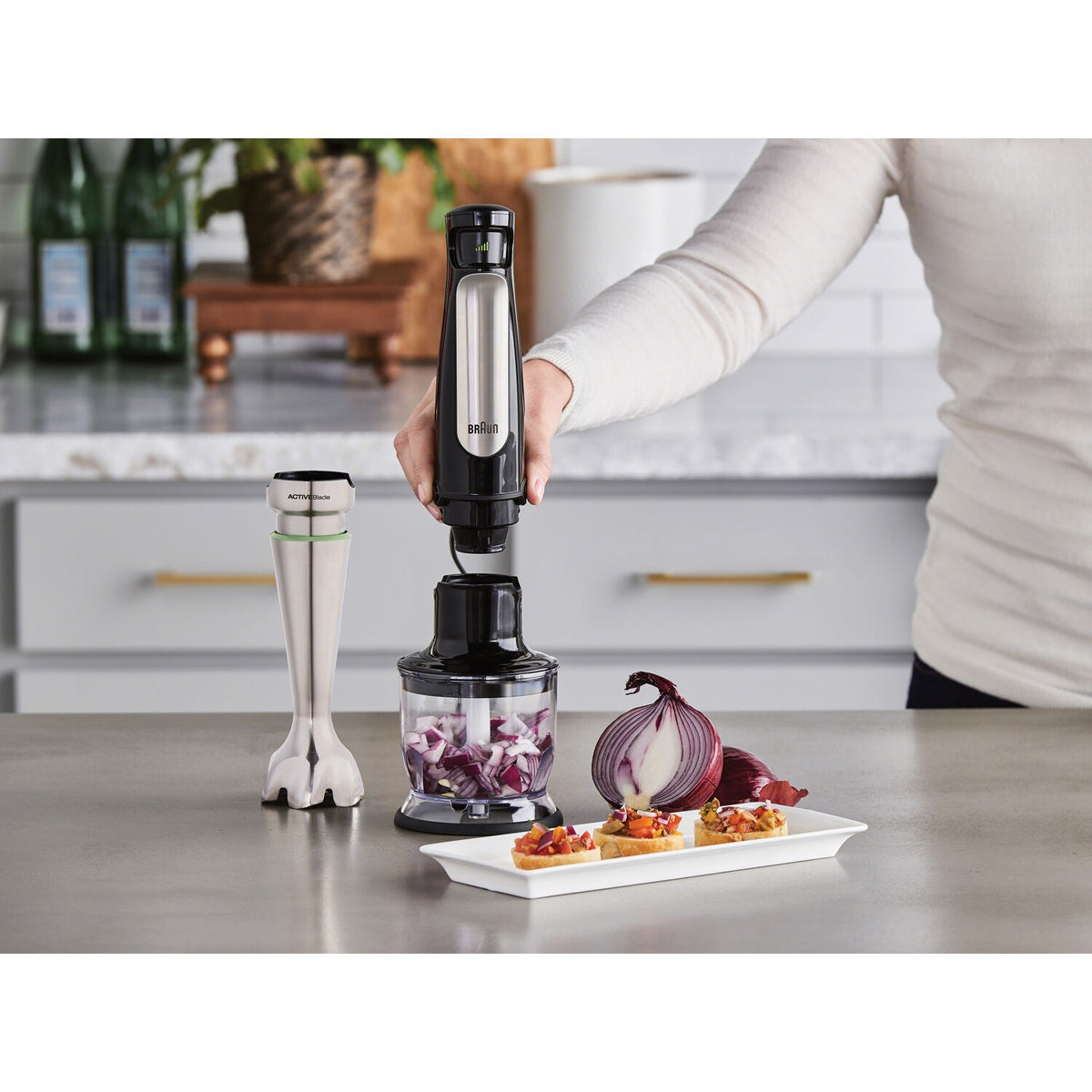 Braun hand blender held above a chopping container and ingredients