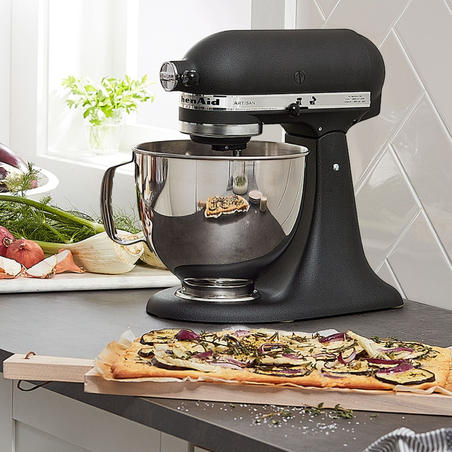 Black tilt-head stand mixer on kitchen counter with stainless mixing bowl