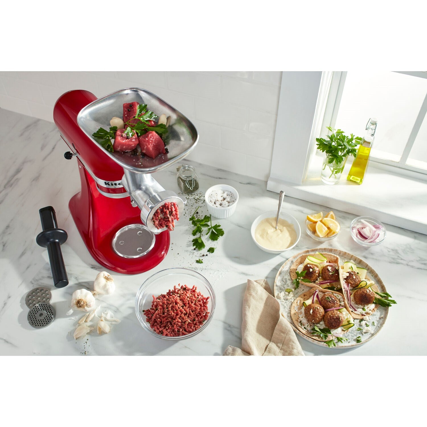 Metal meat grinder attachment with red stand, feeding tube, and grinding plate
