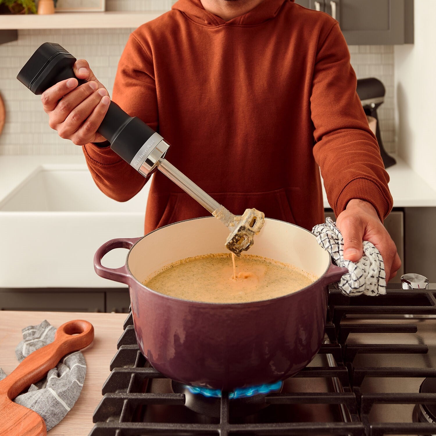 KitchenAid cordless hand blender in use, blending sauce with stainless shaft