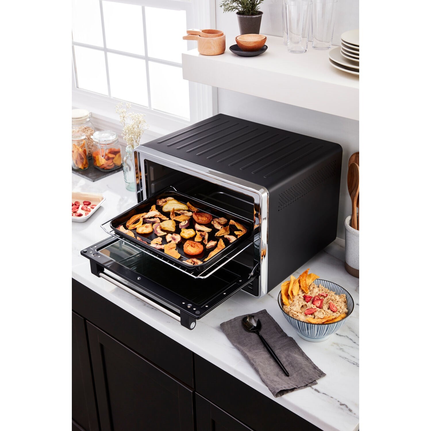 Black countertop oven open on a countertop with tray of browned food