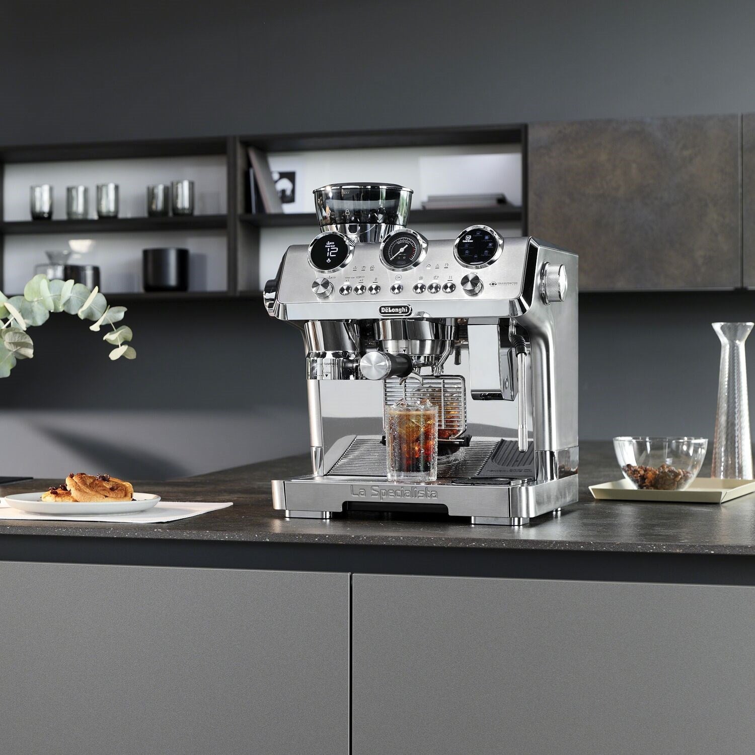 Stainless steel De'Longhi espresso machine on countertop with cups and accessories