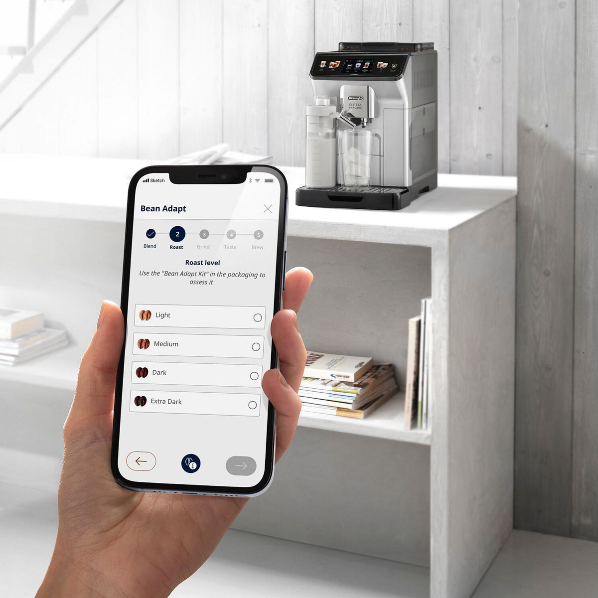 Smartphone in hand showing bean settings for a fully automatic espresso machine
