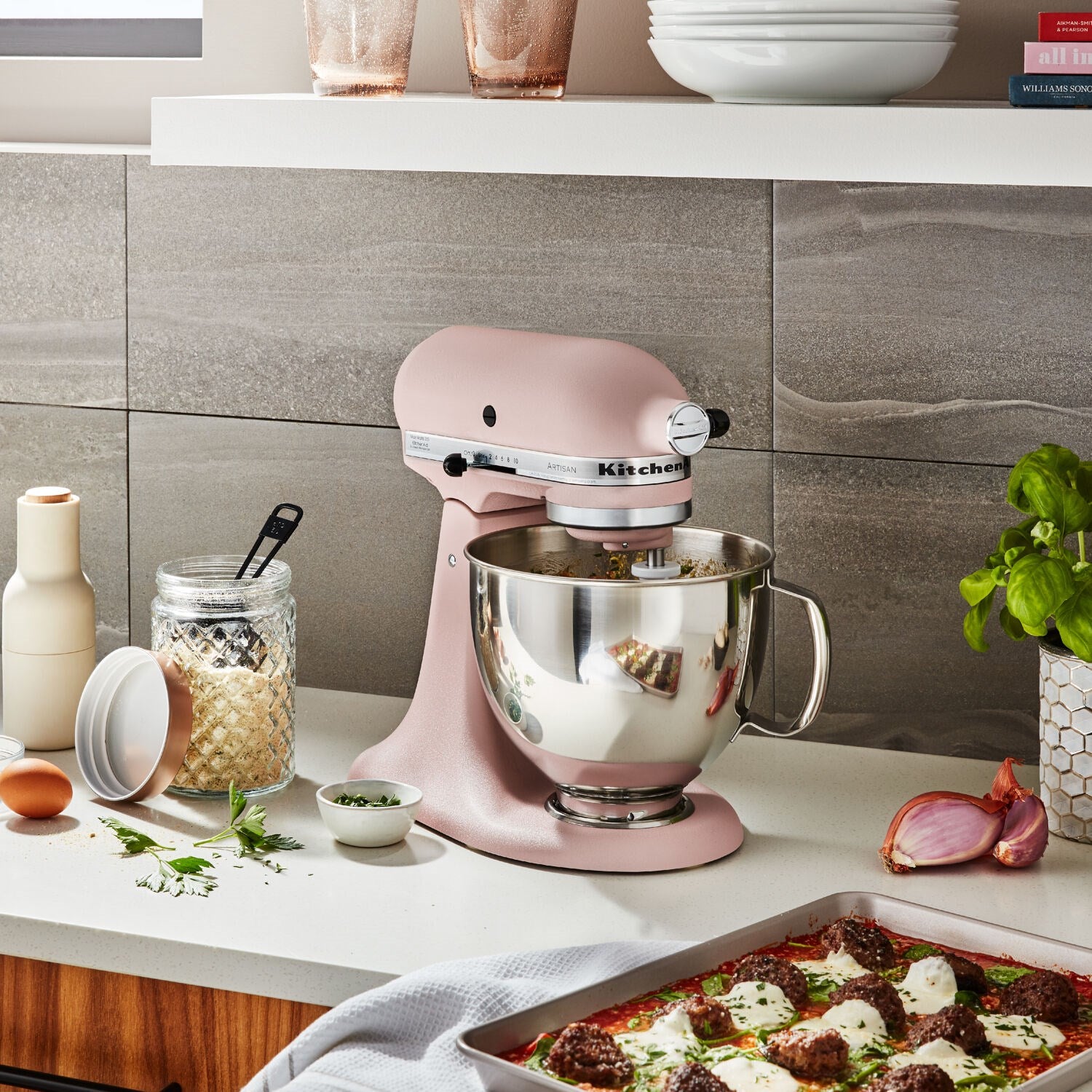 Peach tilt-head stand mixer with stainless bowl; front whisk attachment visible.