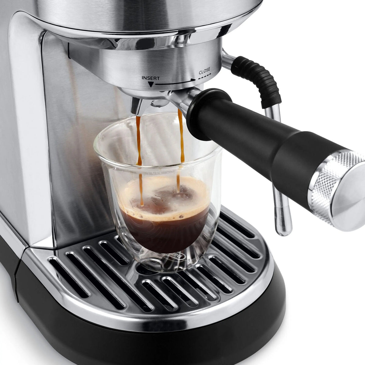 Stainless steel espresso machine with portafilter spouts filling a clear glass with espresso