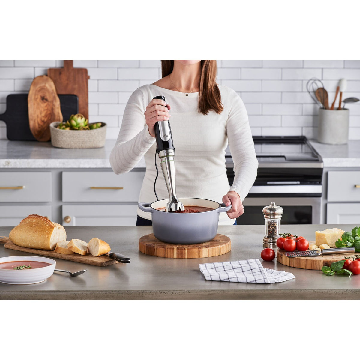 Braun stainless steel hand blender held over a pot on a wooden board