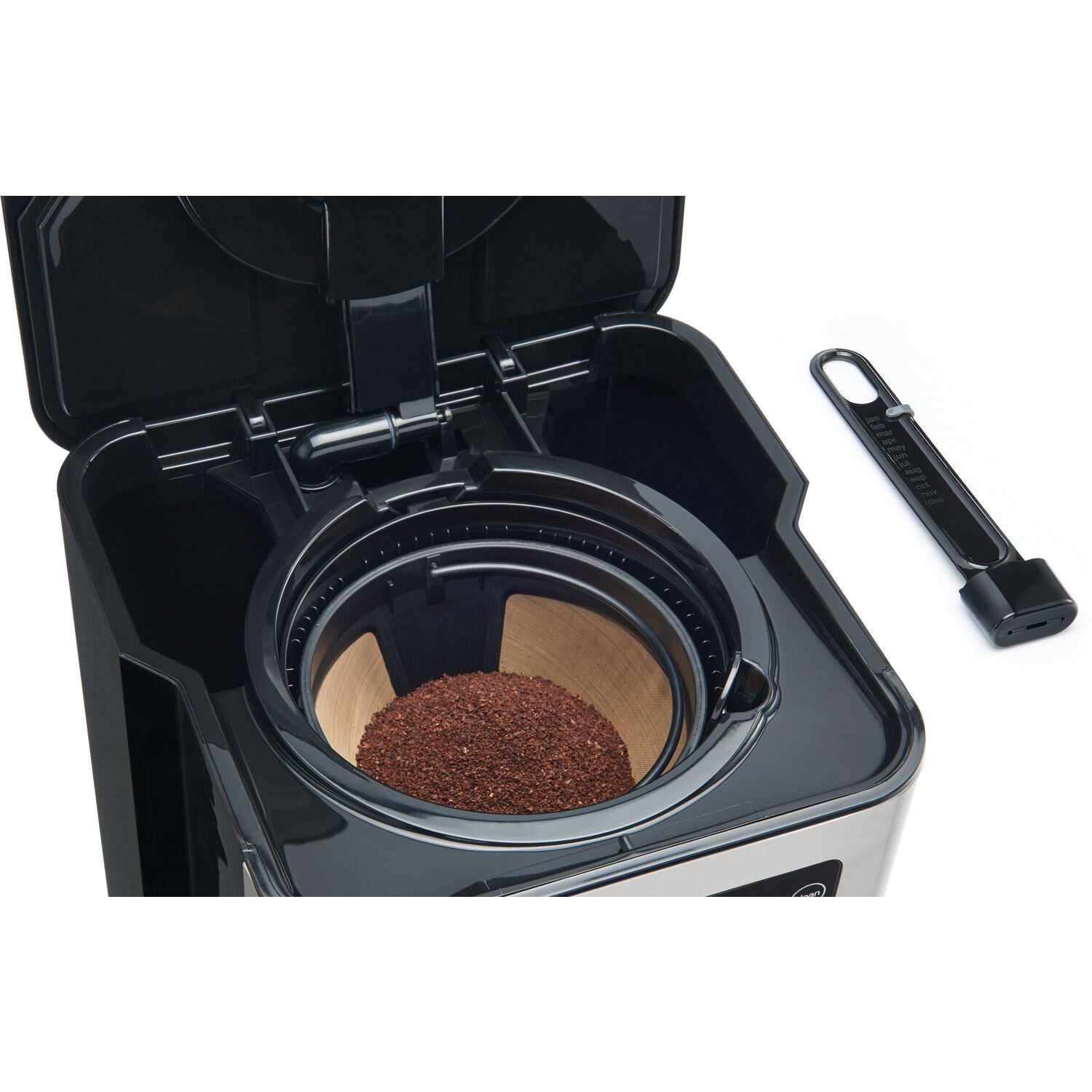 Open filter basket in black iced coffee maker filled with dark coffee grounds