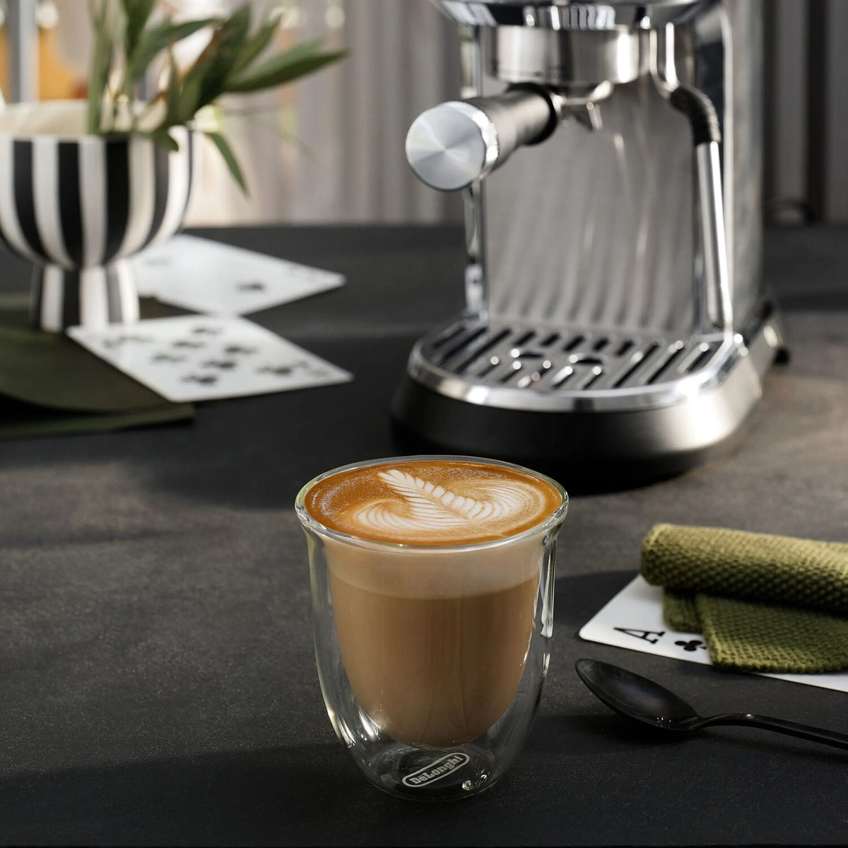 Stainless steel espresso machine making a latte in a clear glass cup