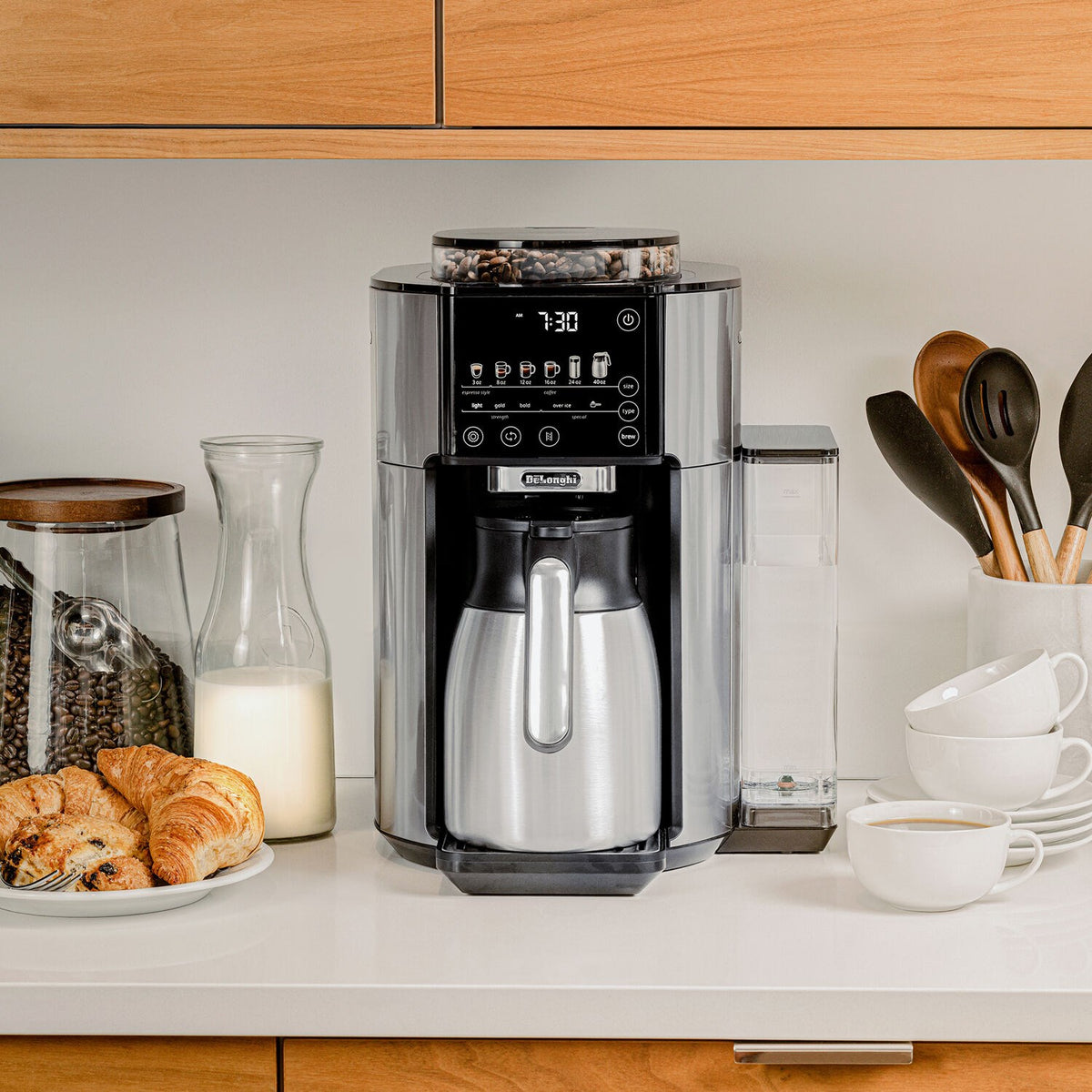De'Longhi TrueBrew automatic coffee maker on countertop with thermal carafe and glass containers