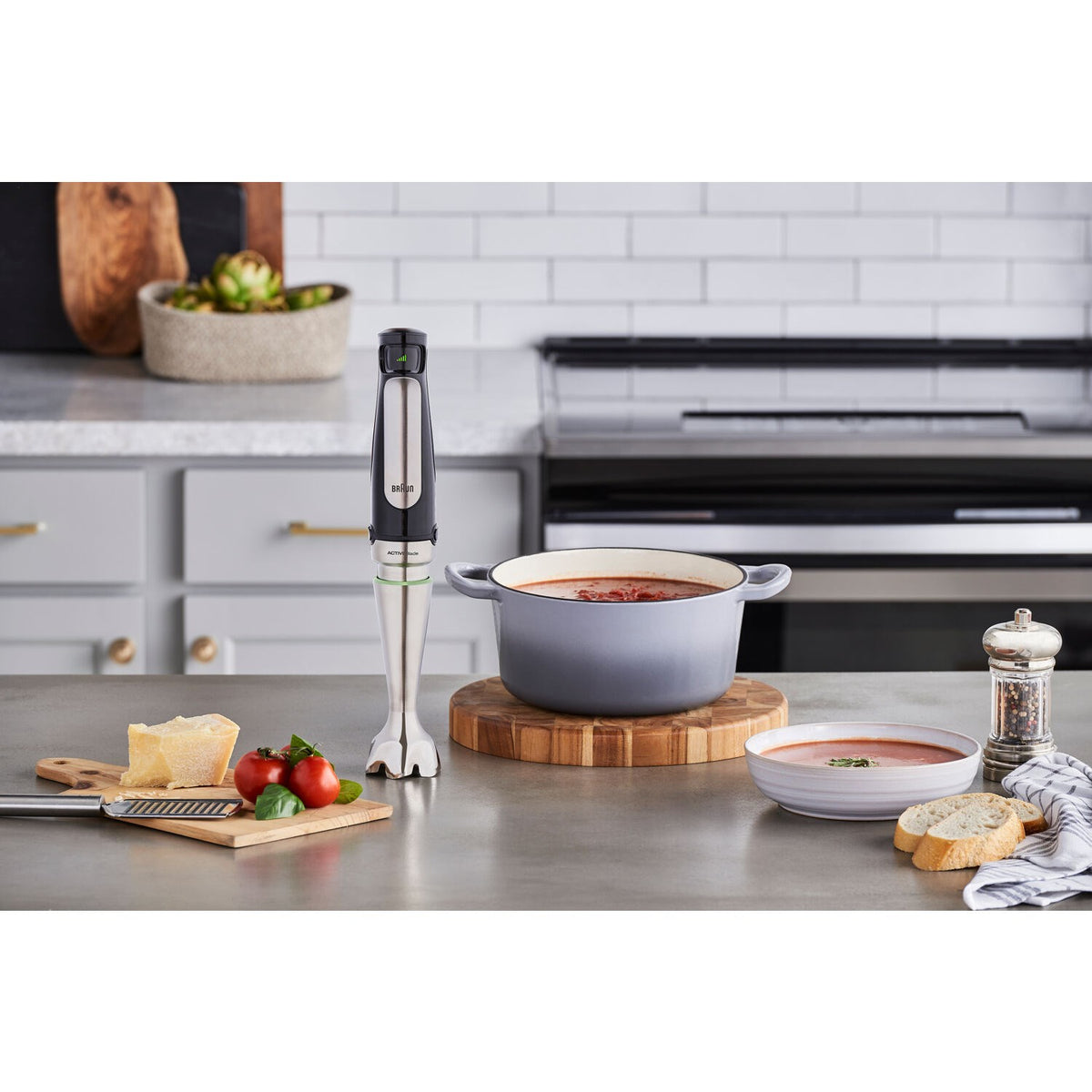 Braun stainless steel hand blender standing on countertop near a pot