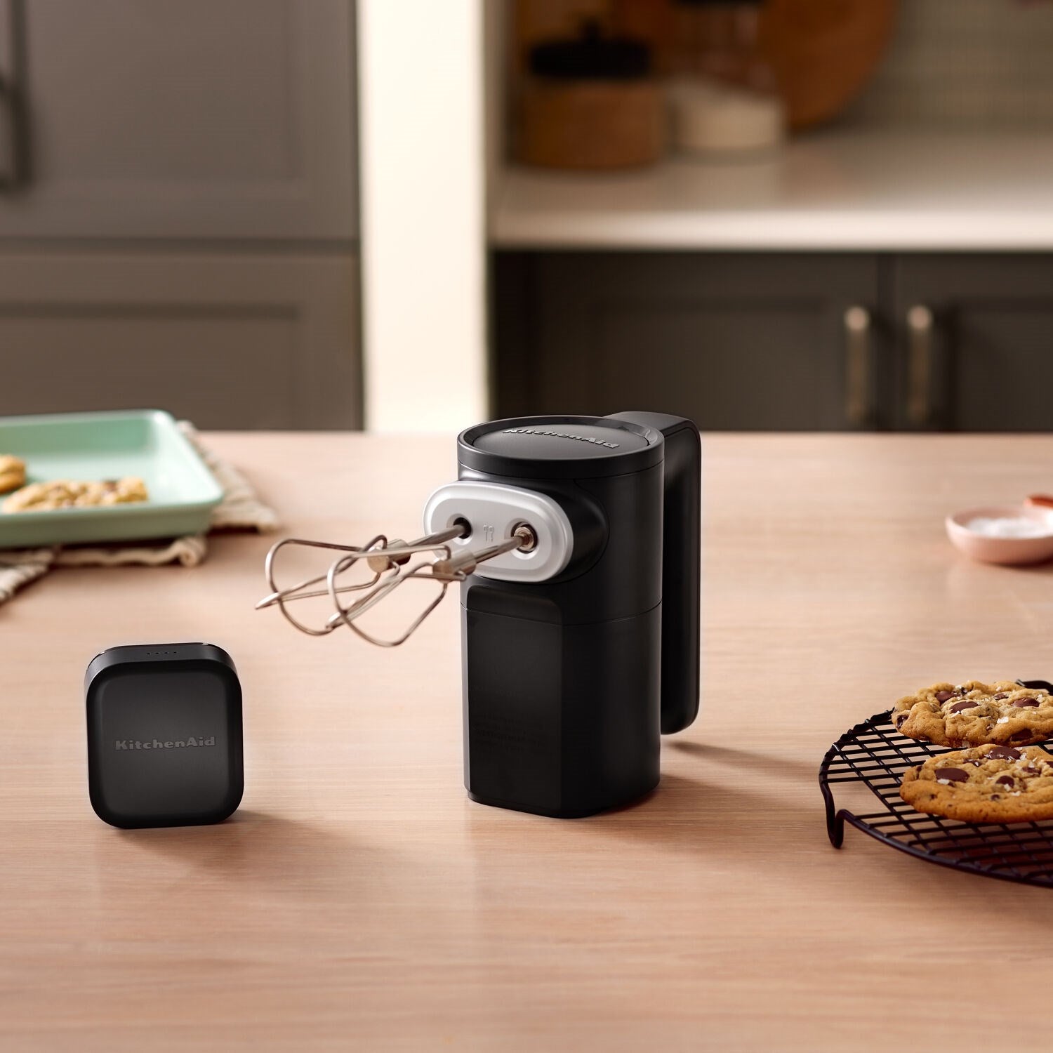Black cordless hand mixer with removable battery pack on a countertop