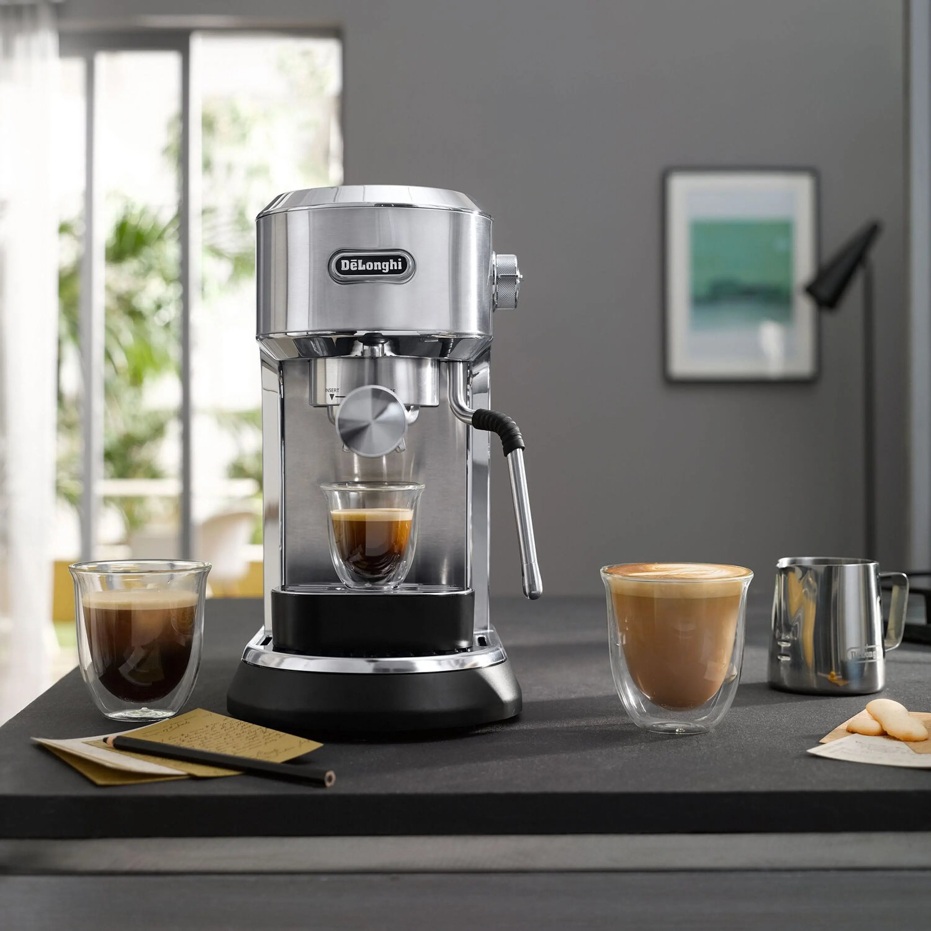 Stainless steel espresso machine with steam wand on kitchen counter, showing brewed cups