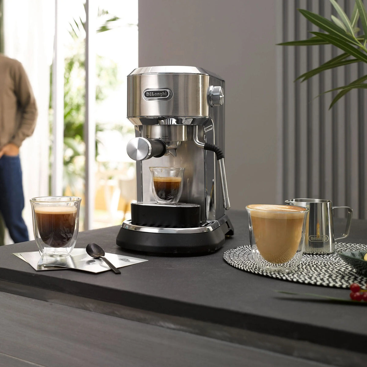 Stainless steel espresso machine on countertop with multiple glasses of espresso and latte