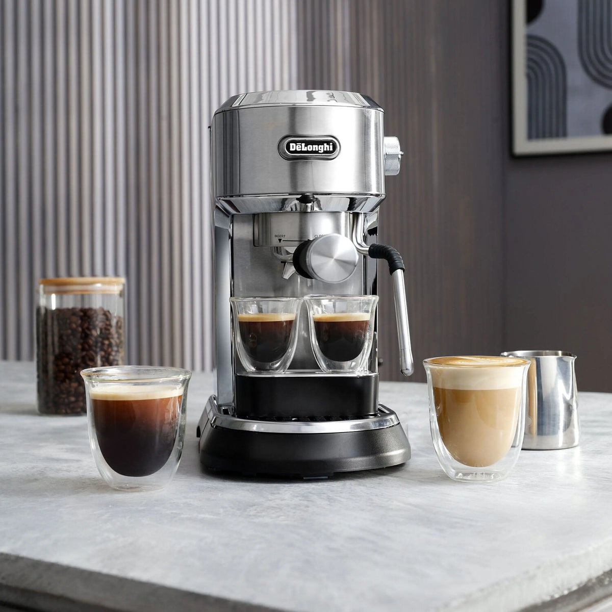 Compact stainless steel espresso machine with steam wand and three filled glass cups