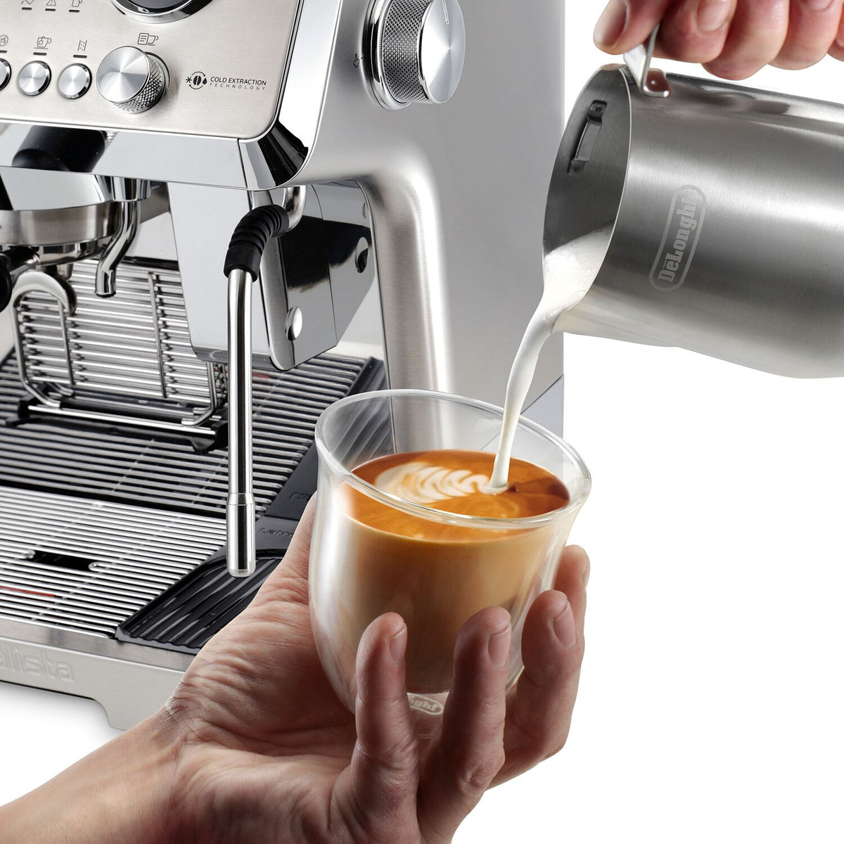 Espresso machine steam wand pouring latte into clear cup with latte art