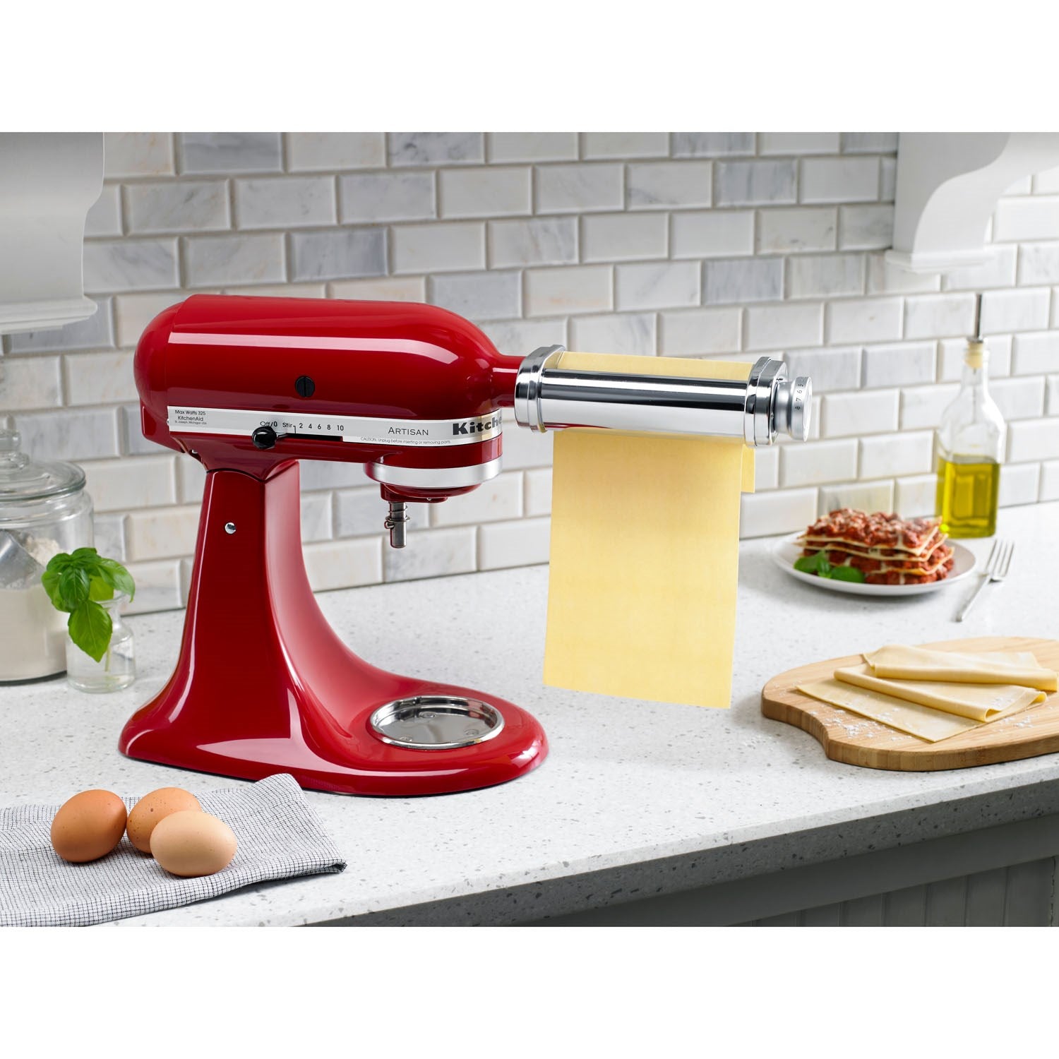 KitchenAid mixer pasta roller attachment with red body, silver drum, and yellow dough sheet
