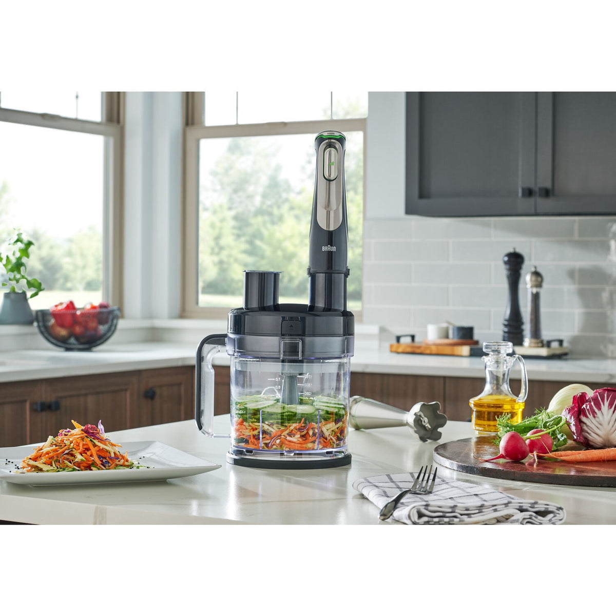 Hand blender with stainless-steel and black shaft blending shredded vegetables in a bowl