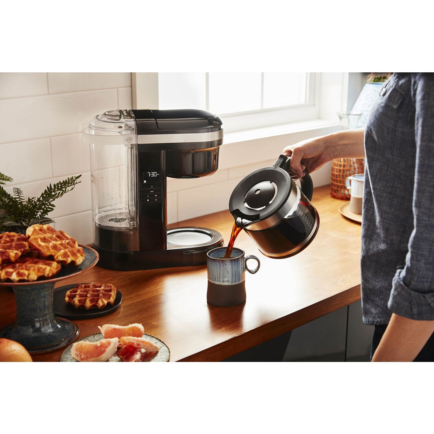 KitchenAid 12-cup drip coffee brewer, Onyx black, near mugs and carafe on counter