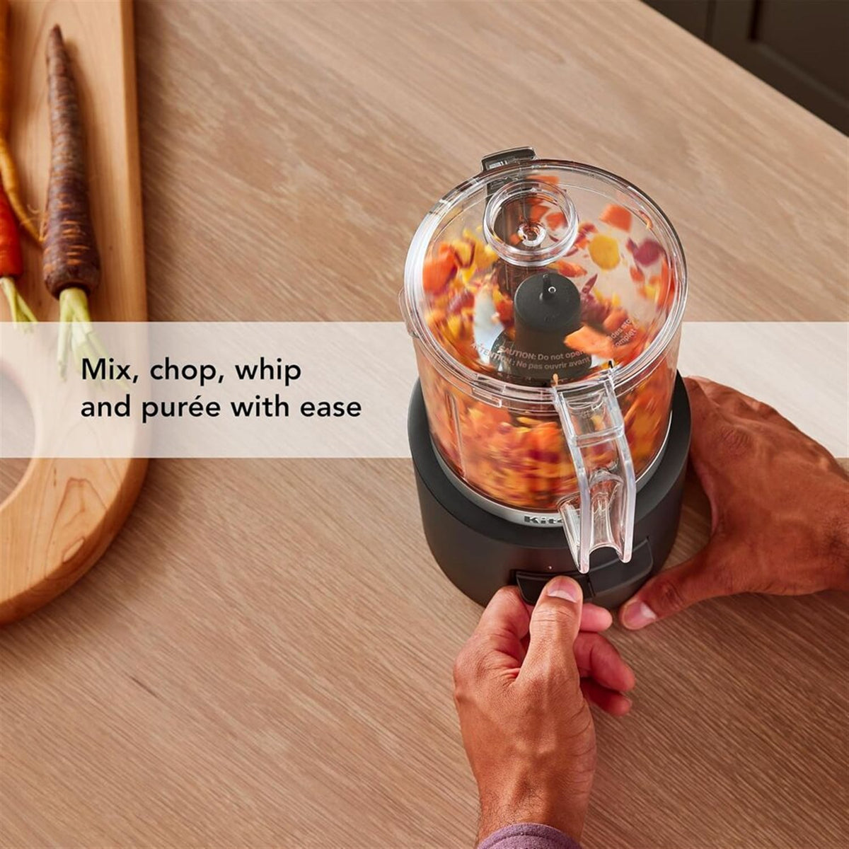 Black matte cordless chopper with clear bowl containing blended ingredients