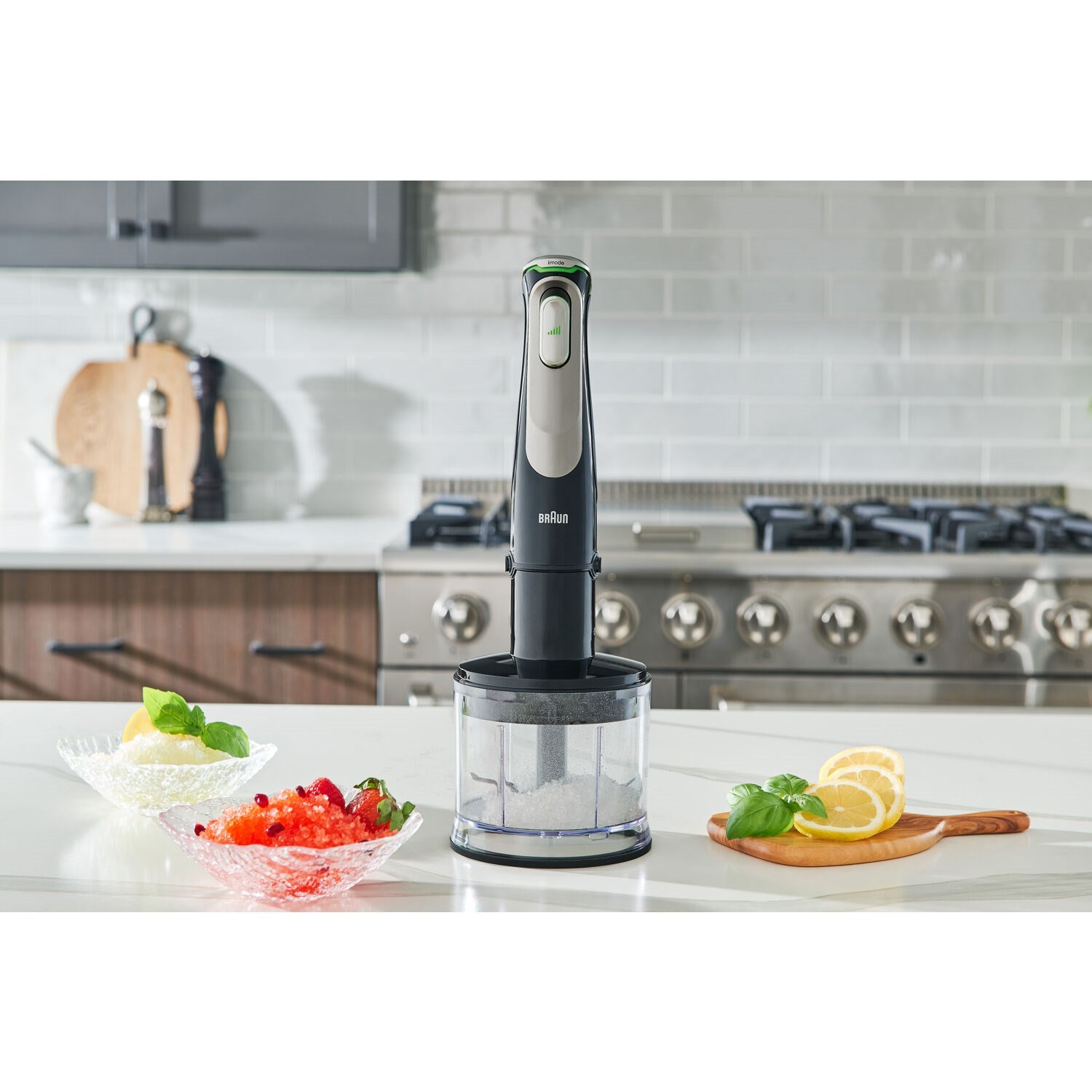 Braun hand blender with blending shaft and chopper cup, on a kitchen counter.