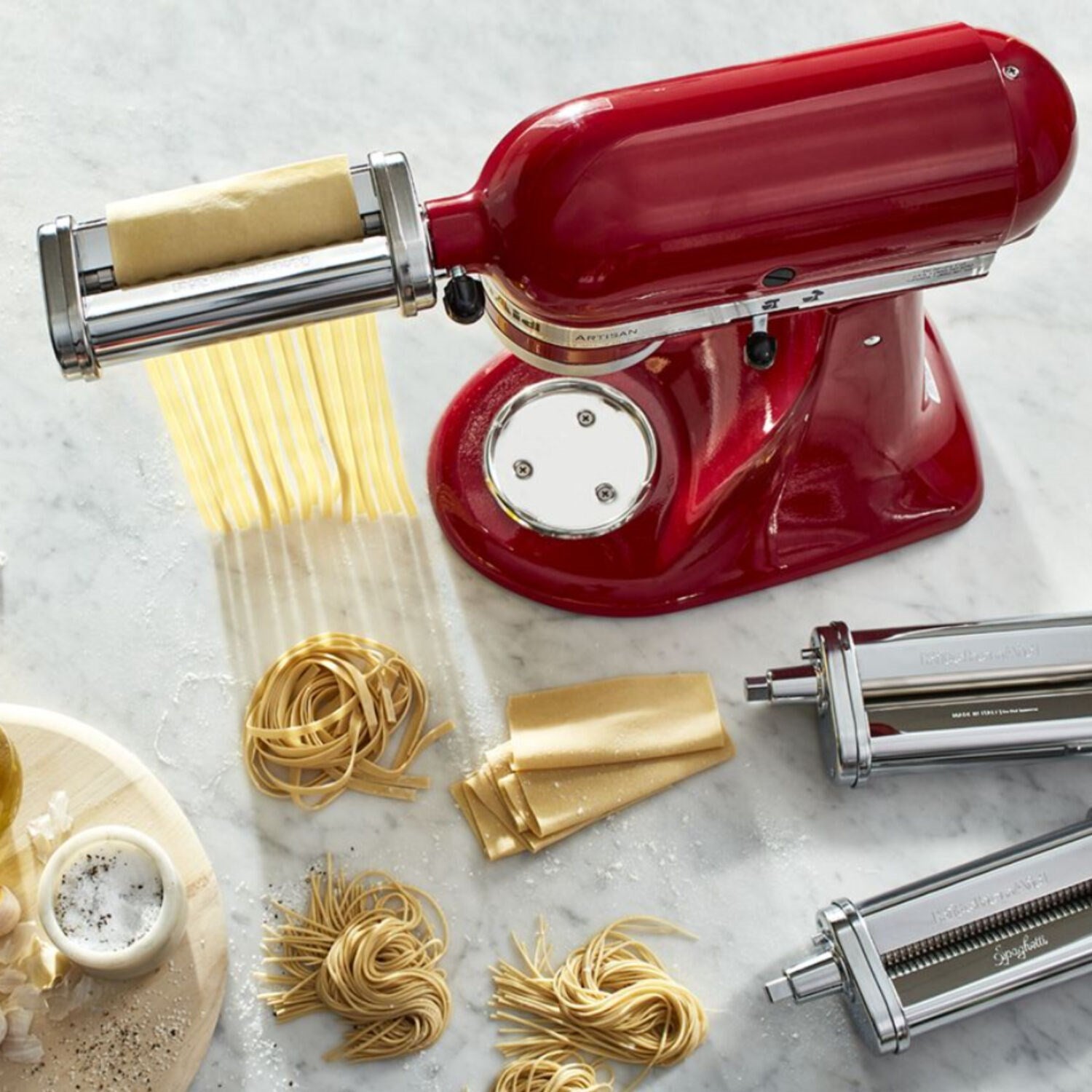 Red stand mixer pasta roller attachment with dough feed and yellow noodles