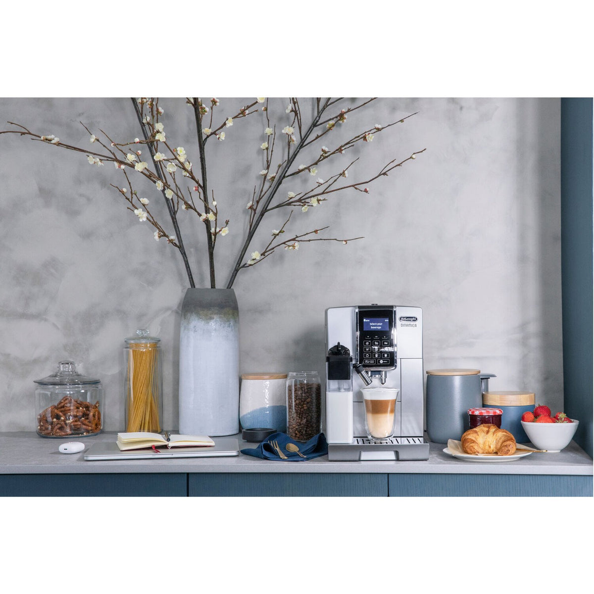 Silver super-automatic espresso machine on sideboard with cups and coffee items