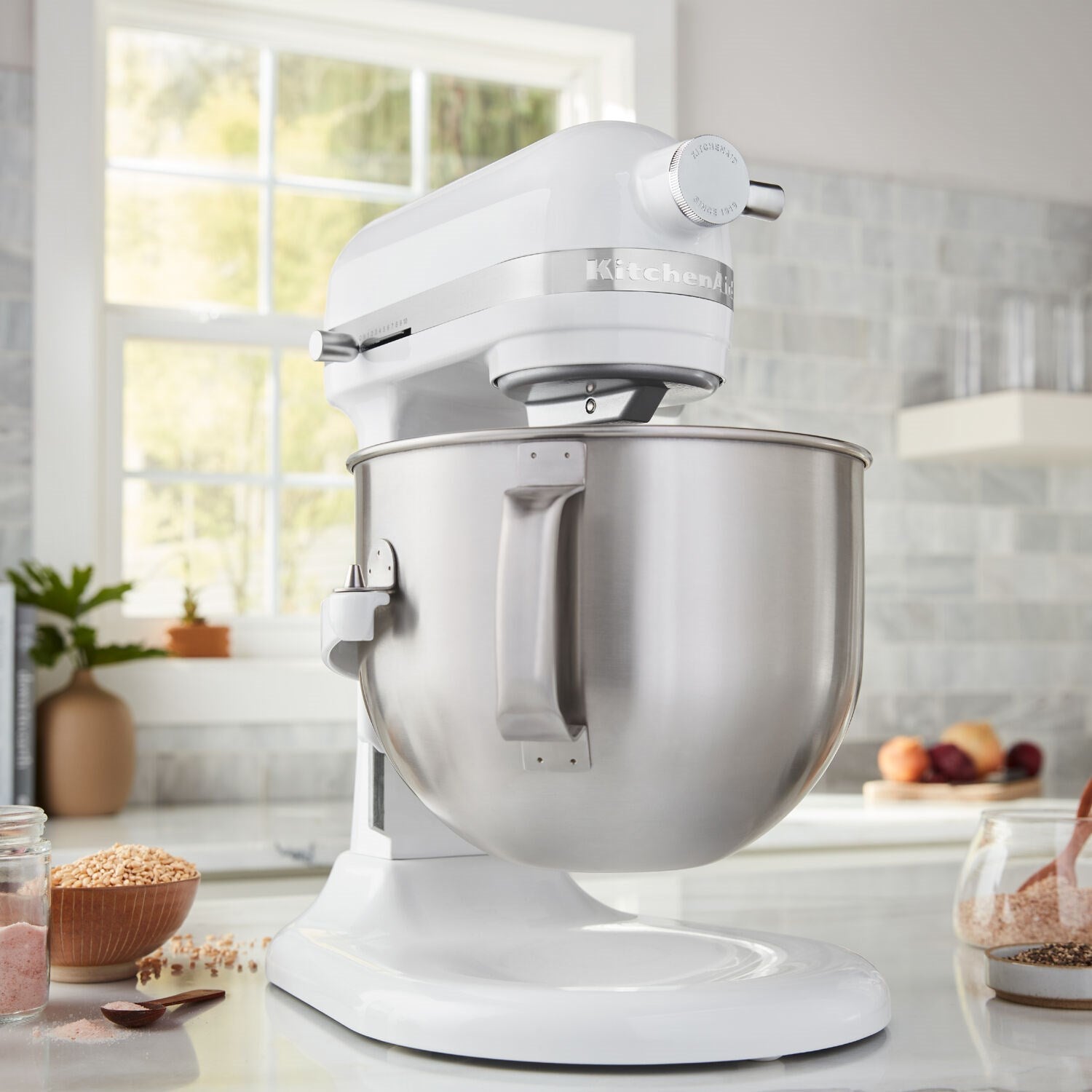 White KitchenAid stand mixer with stainless bowl and bowl-lift beater attachment, side view