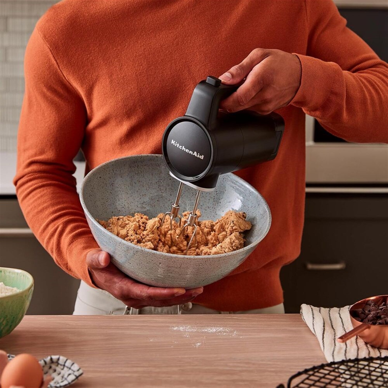 KitchenAid cordless hand mixer whipping dough in a bowl, black matte handle