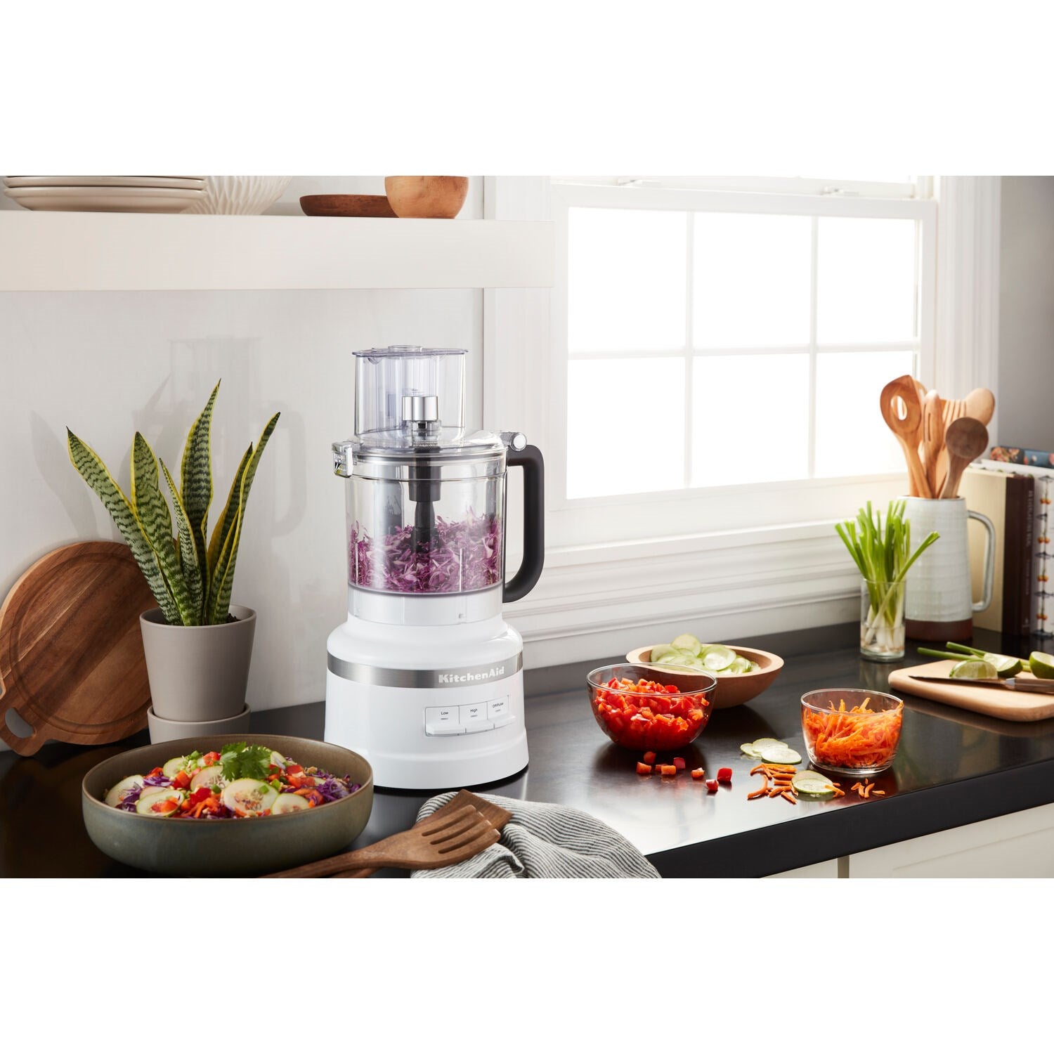 KitchenAid white food processor with clear bowl on countertop, black handle visible