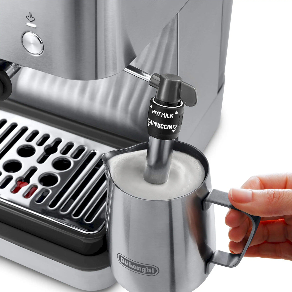 Milk frother steam wand above metal cup, hand adjusting control on espresso machine