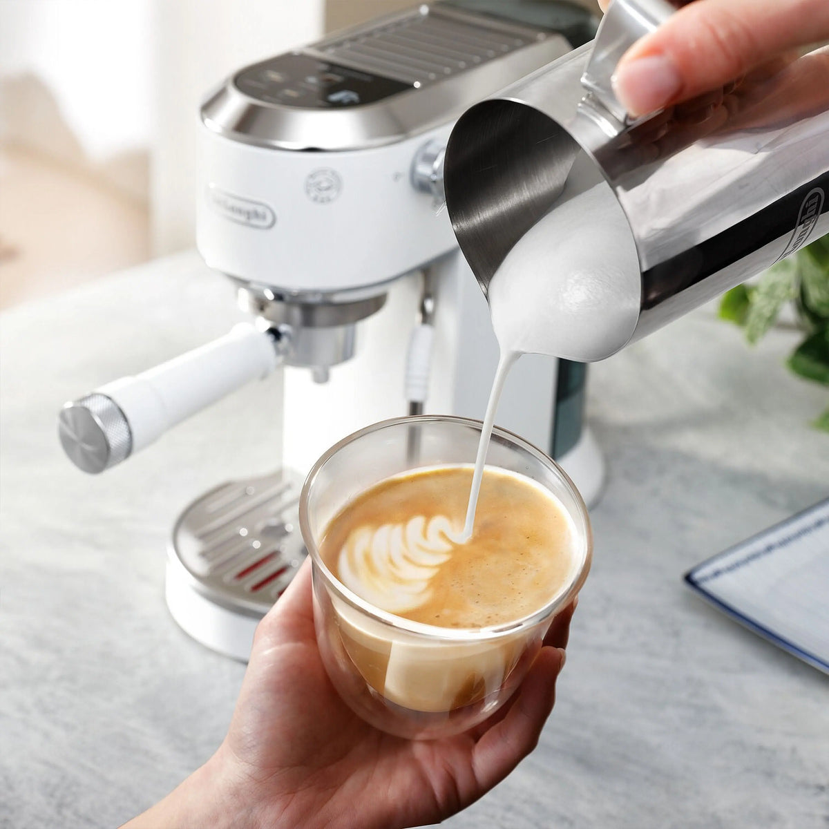 De'Longhi espresso machine with frothing wand steaming vanilla milk into a cup