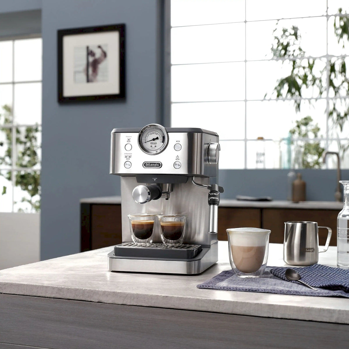 Automatic espresso machine on countertop with cups and metal milk jug nearby