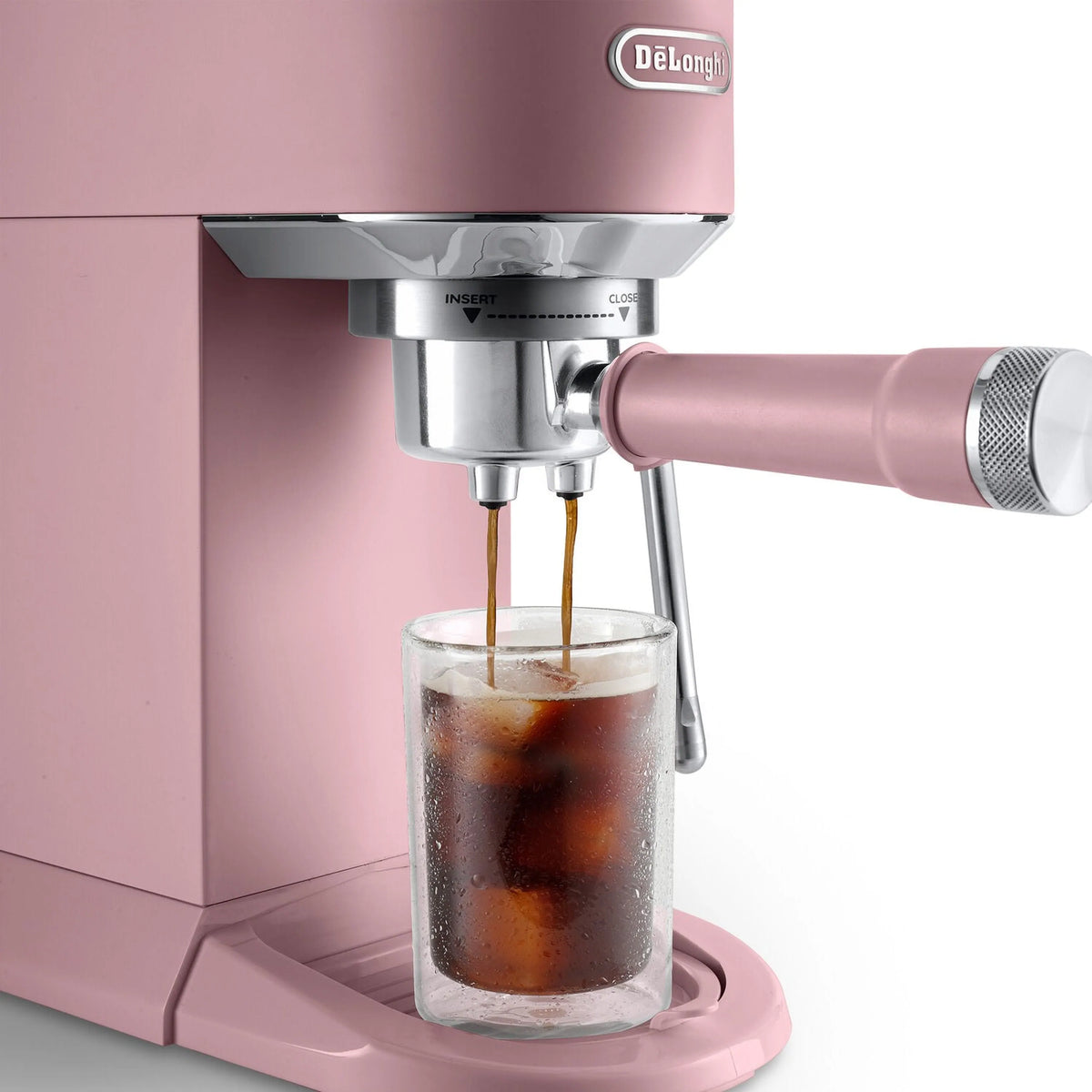 Pink espresso machine pouring into a glass cup with cold brew coffee