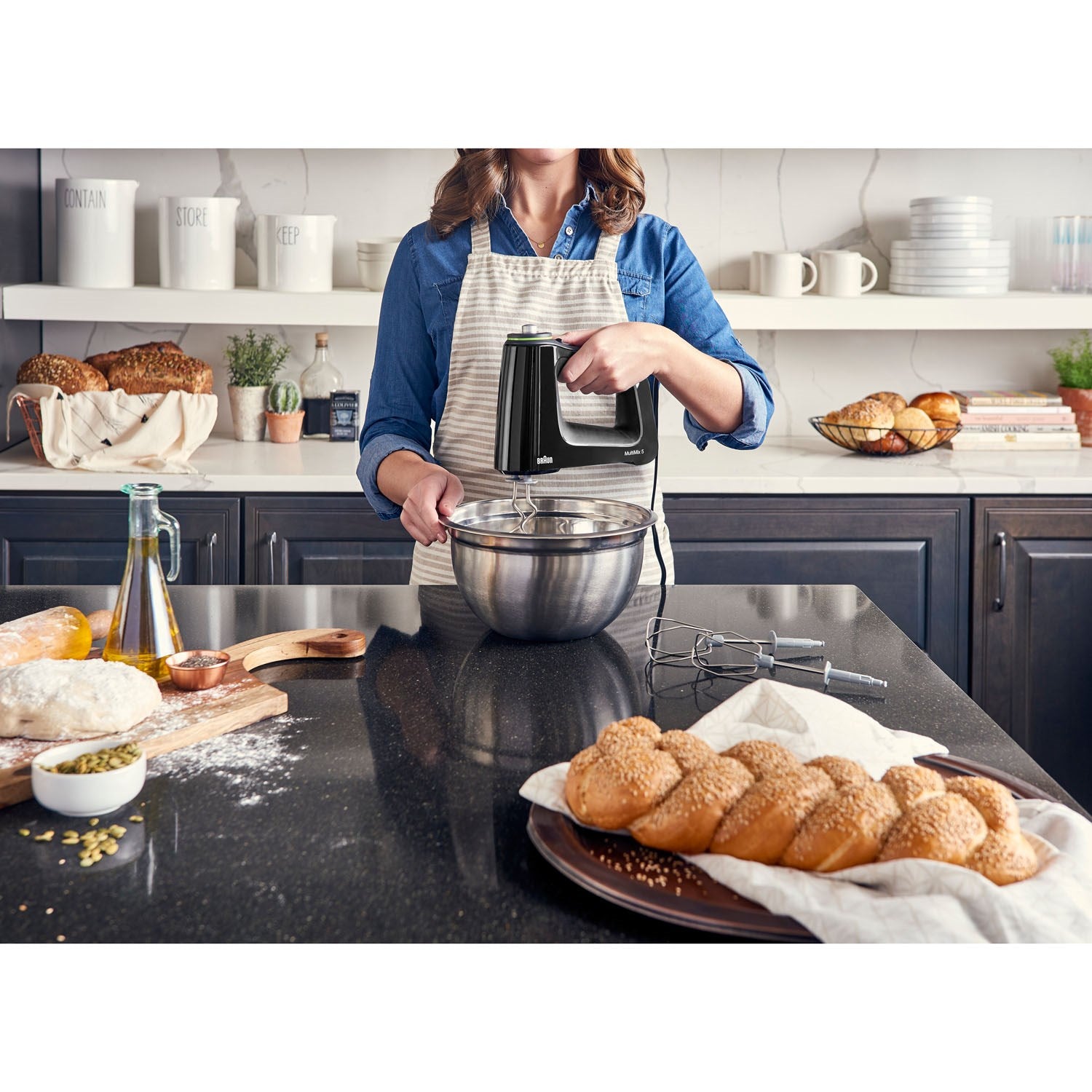 Black hand mixer held above a metal mixing bowl with beaters attached.