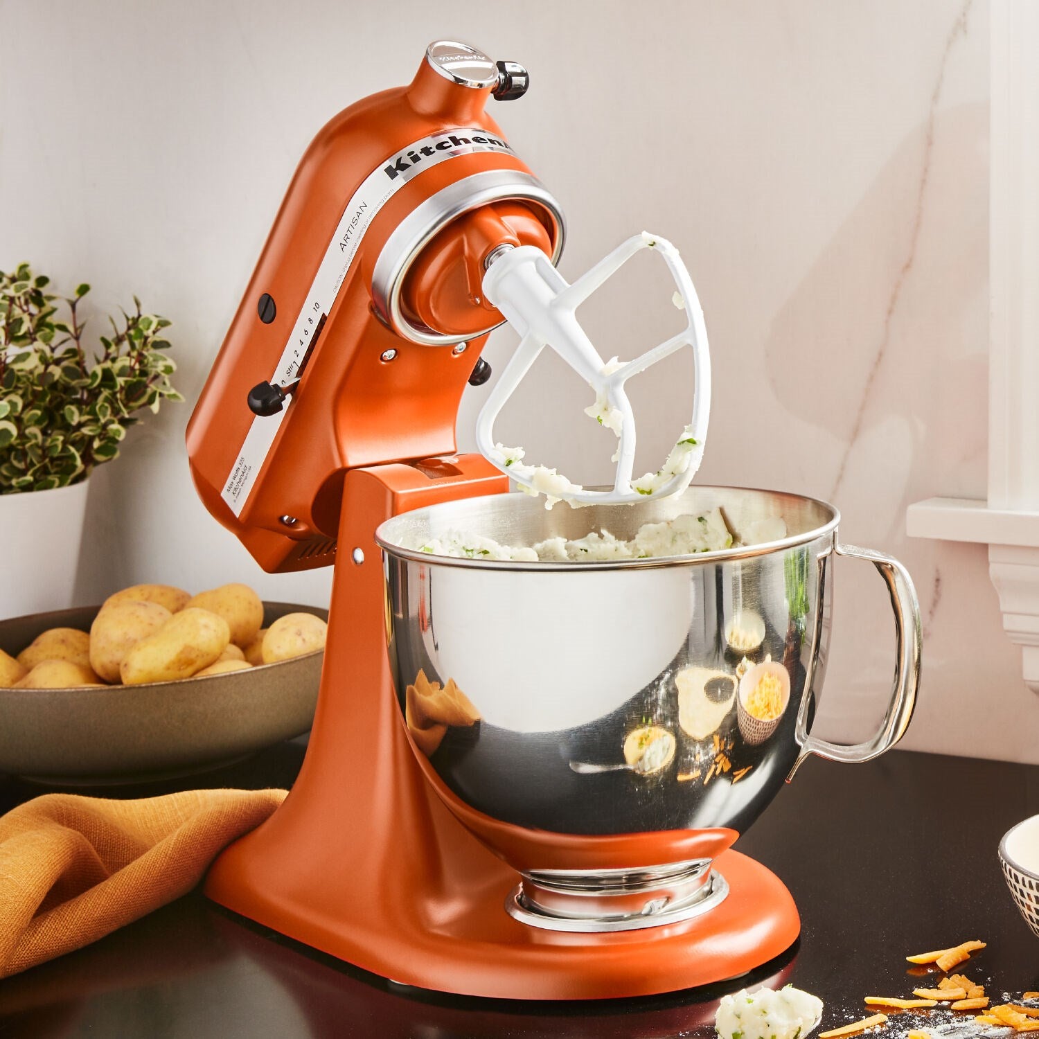KitchenAid Artisan tilt-head stand mixer in scorched orange with whisk attachment and bowl