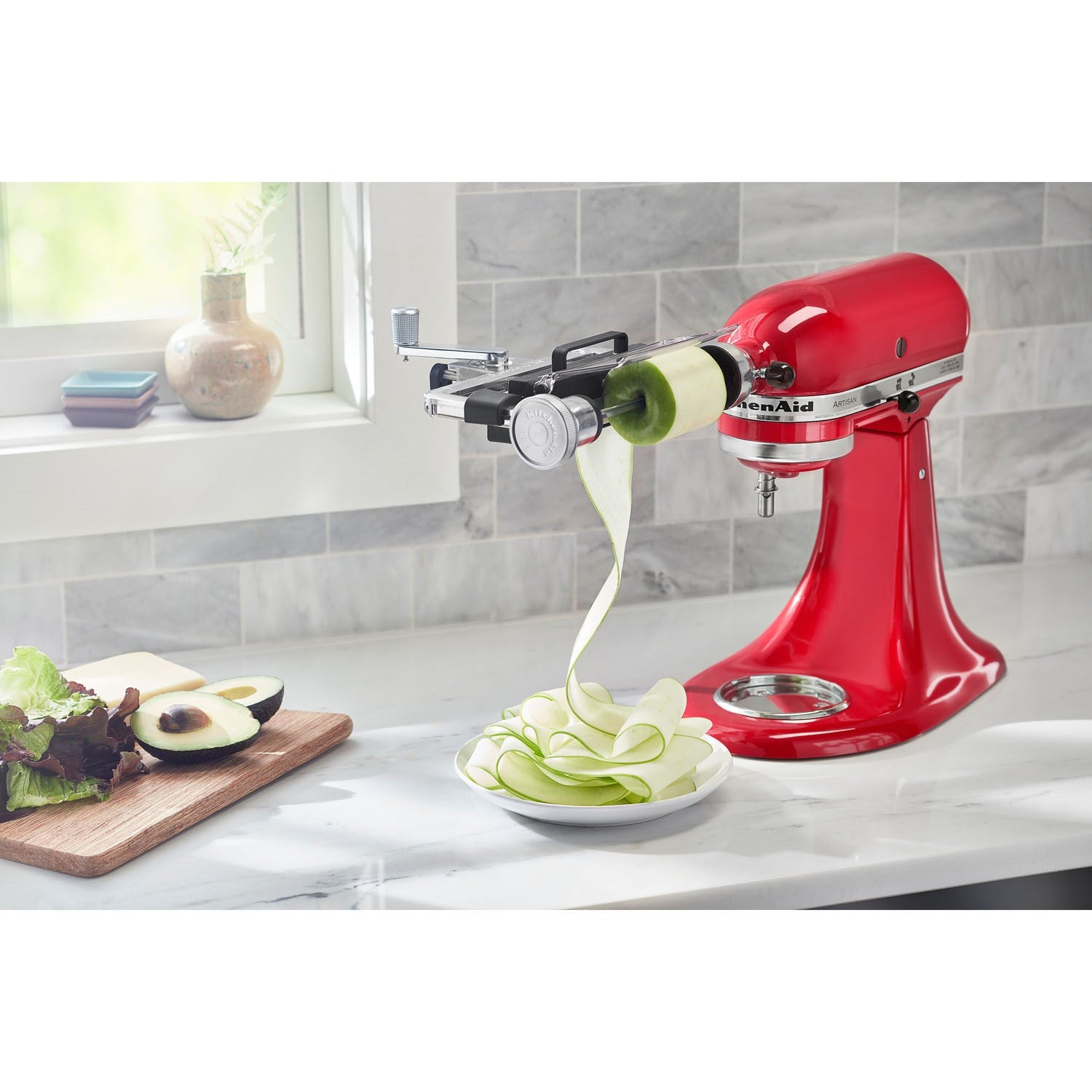 Vegetable sheet cutter attachment cutting zucchini ribbons on red stand mixer