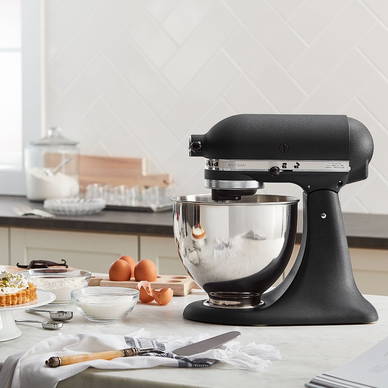 Black tilt-head stand mixer with stainless bowl, glossy black base