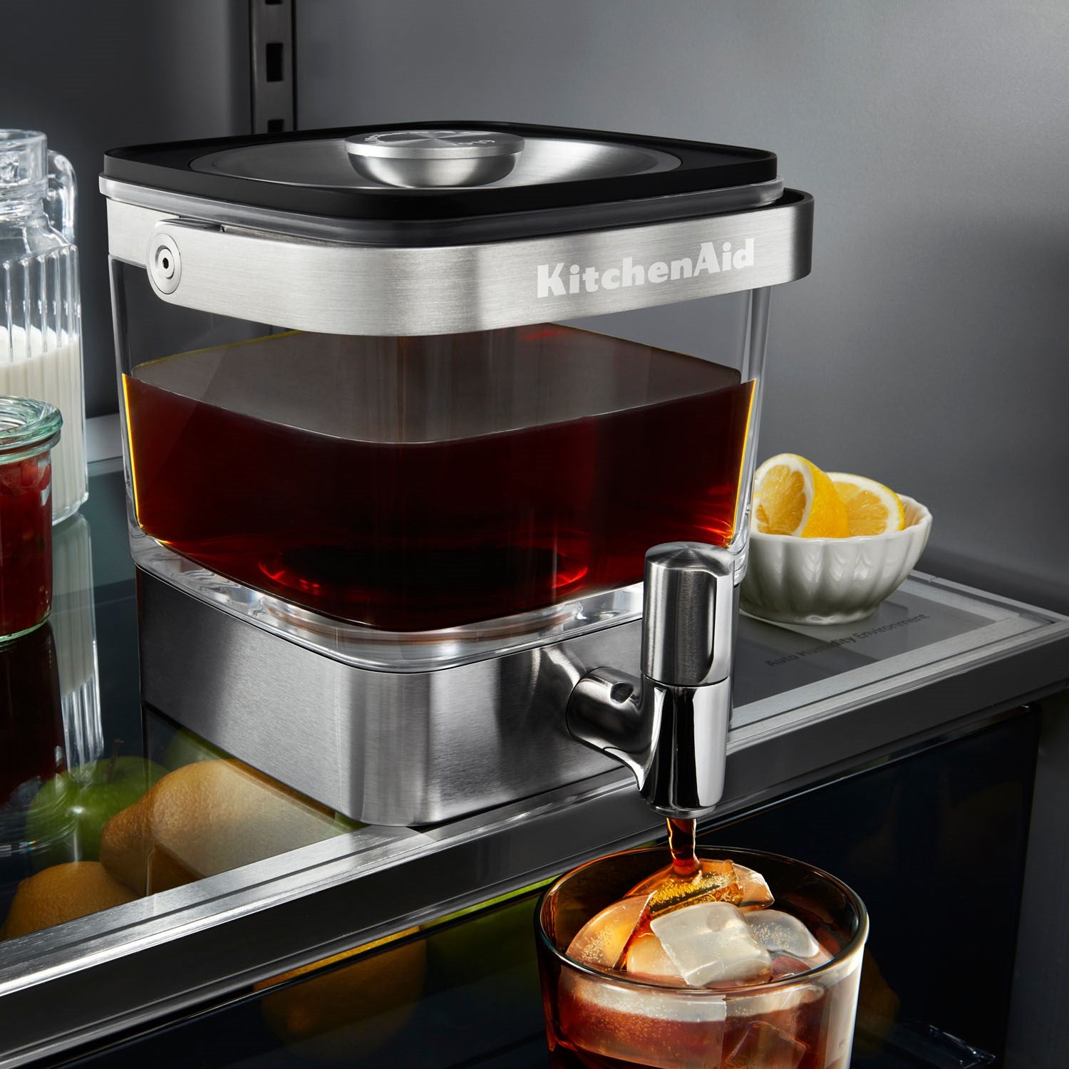 Stainless cold brew coffee maker dispensing dark brew into a glass cup
