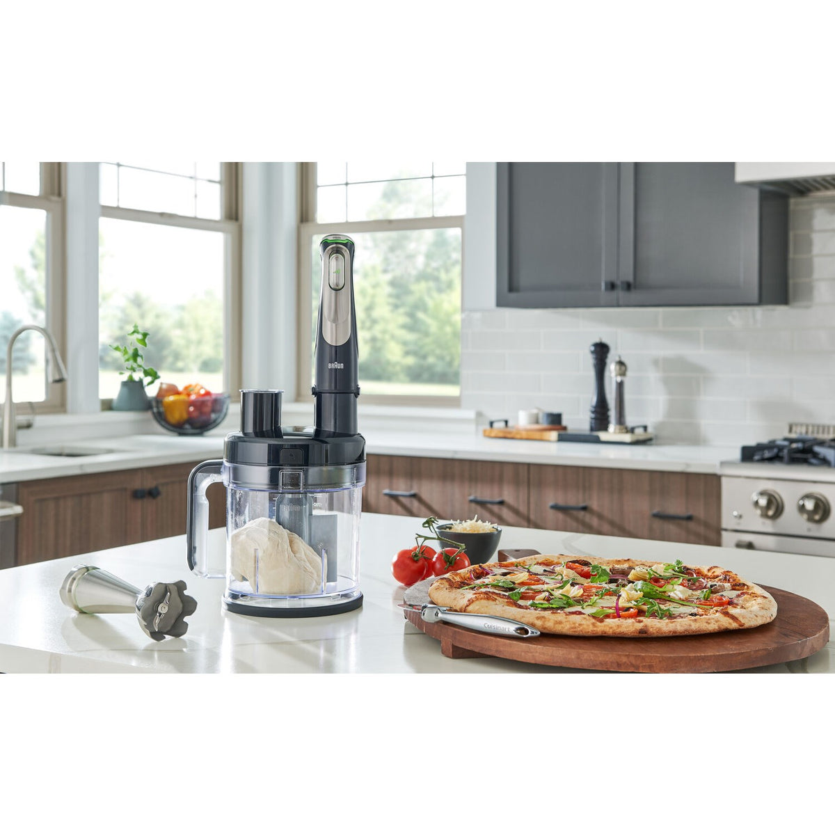 Hand blender with clear chopper cup and blending shaft on a kitchen counter