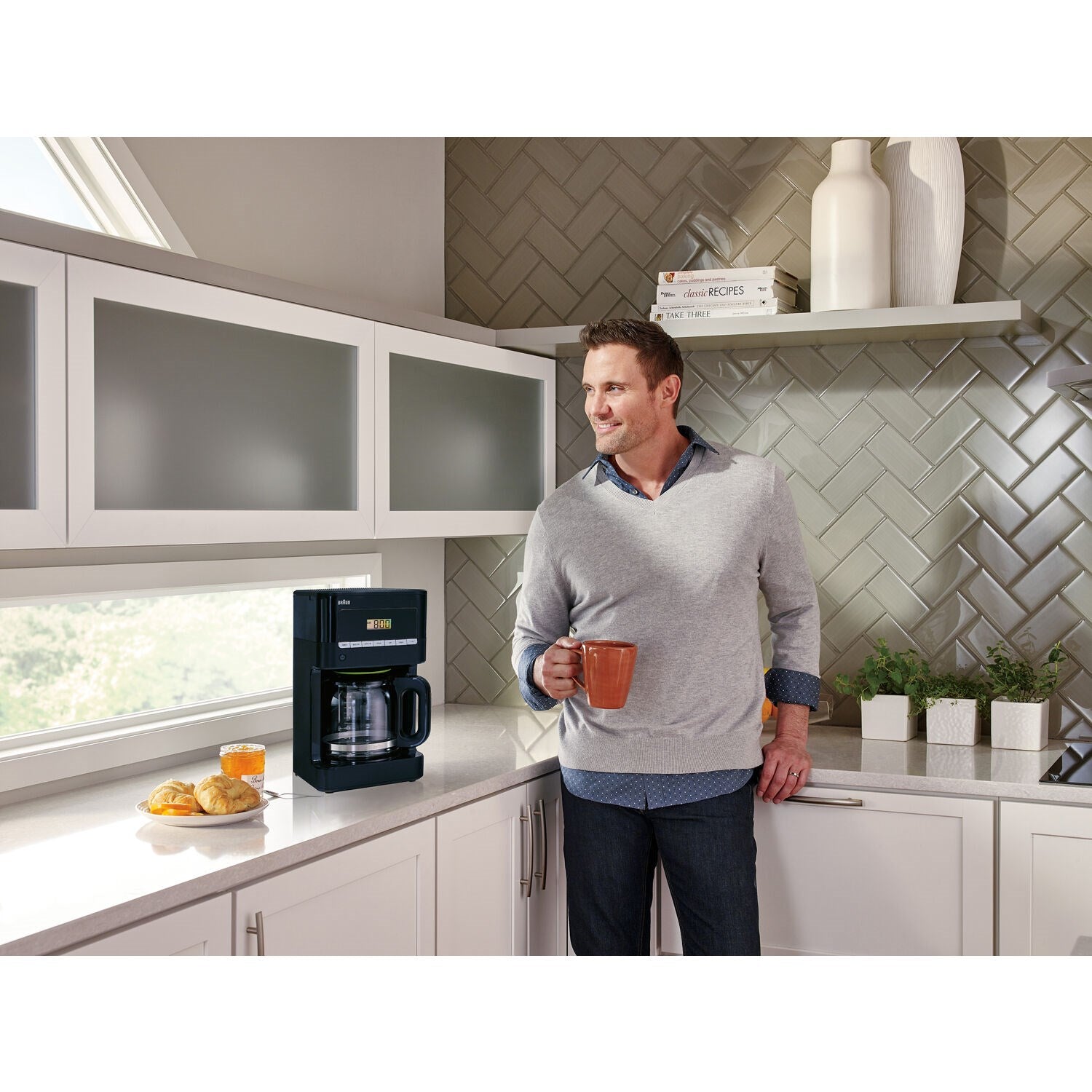 Black Braun 12-cup drip coffee maker beside man holding a mug in kitchen