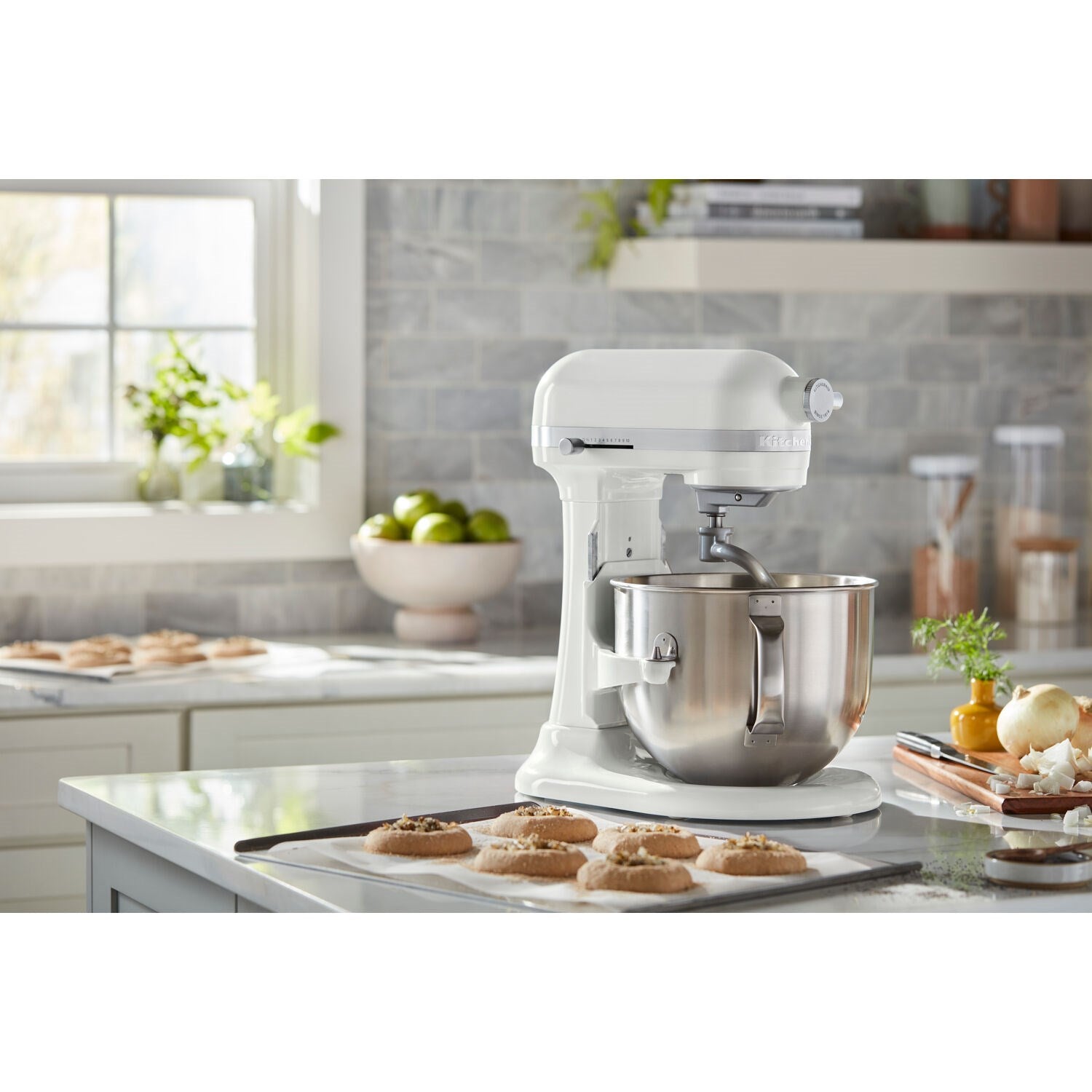 White KitchenAid stand mixer with stainless bowl on kitchen counter