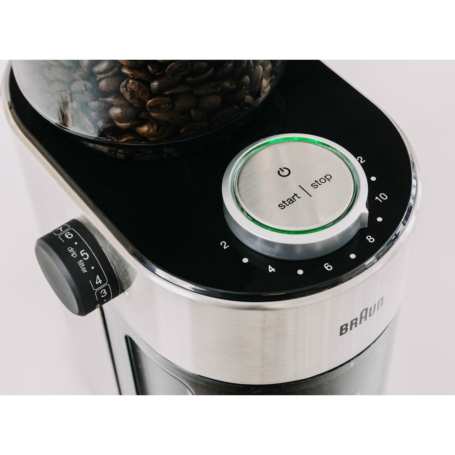 Burr coffee grinder top dial and start/stop button with beans in the hopper